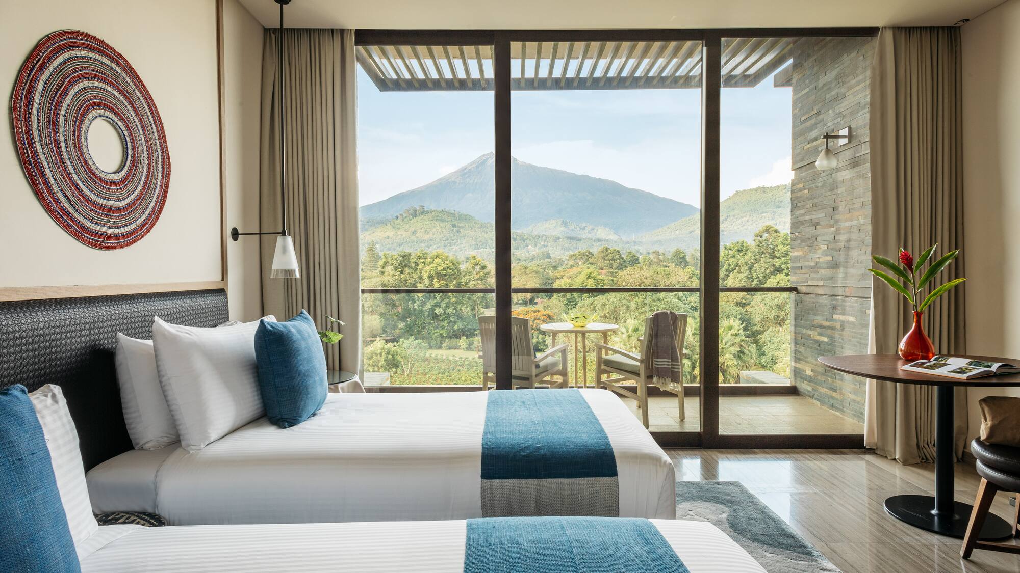 two beds in a room with a view of mountains and trees