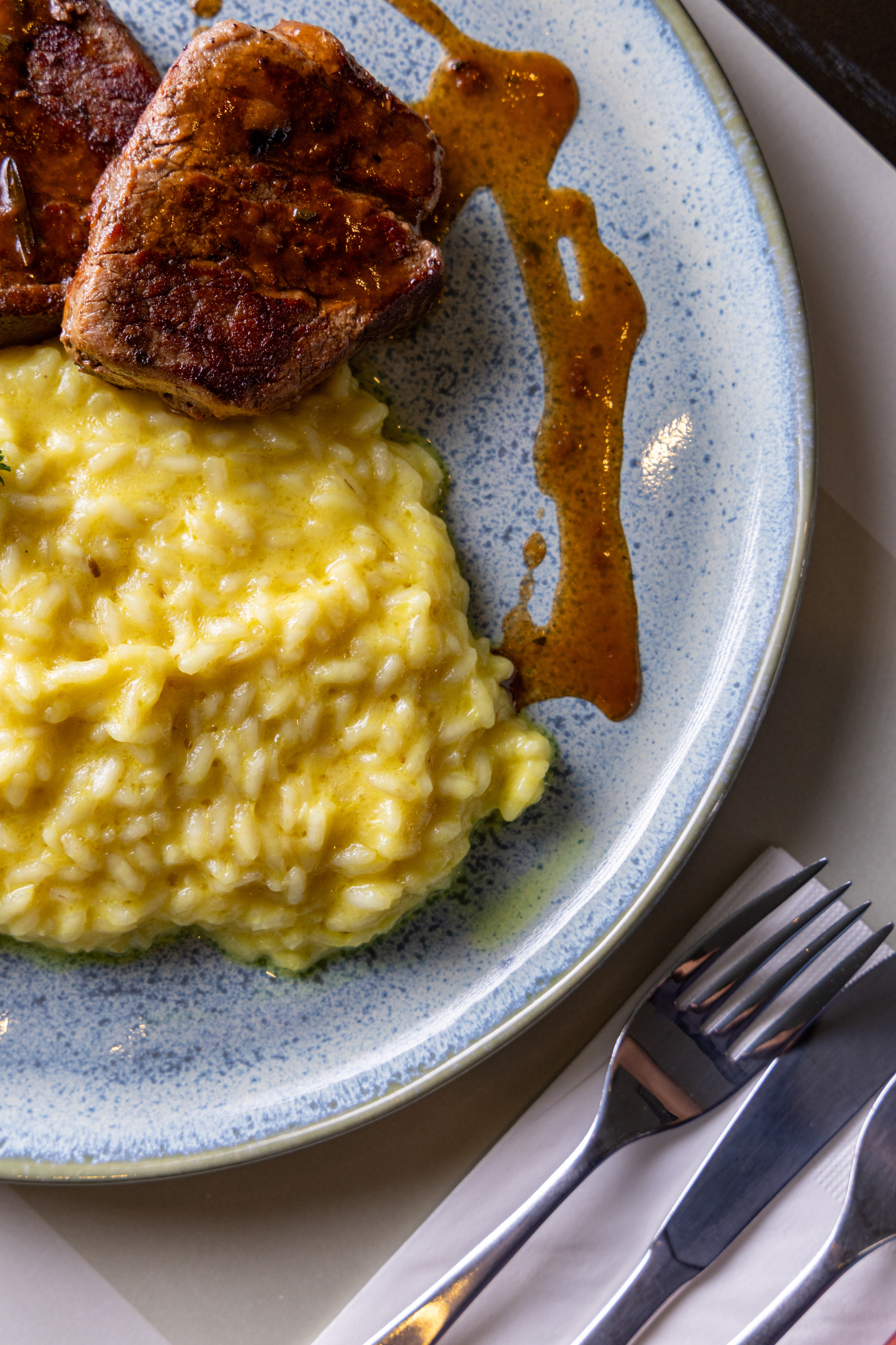 Seared pork loin, creamy yellow risotto, and savory sauce.