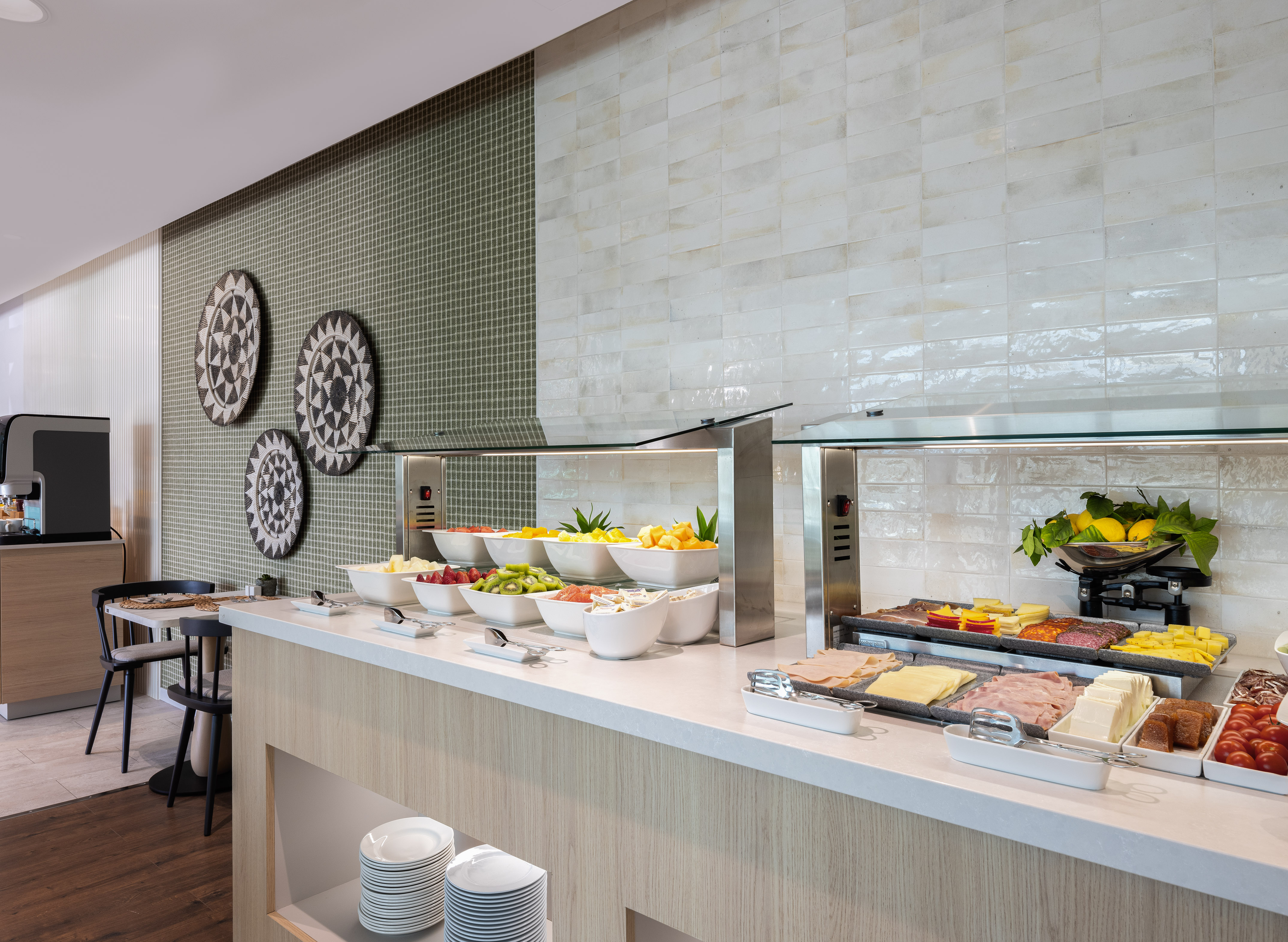 Modern hotel breakfast buffet with fresh fruit, cold cuts, and cheeses.