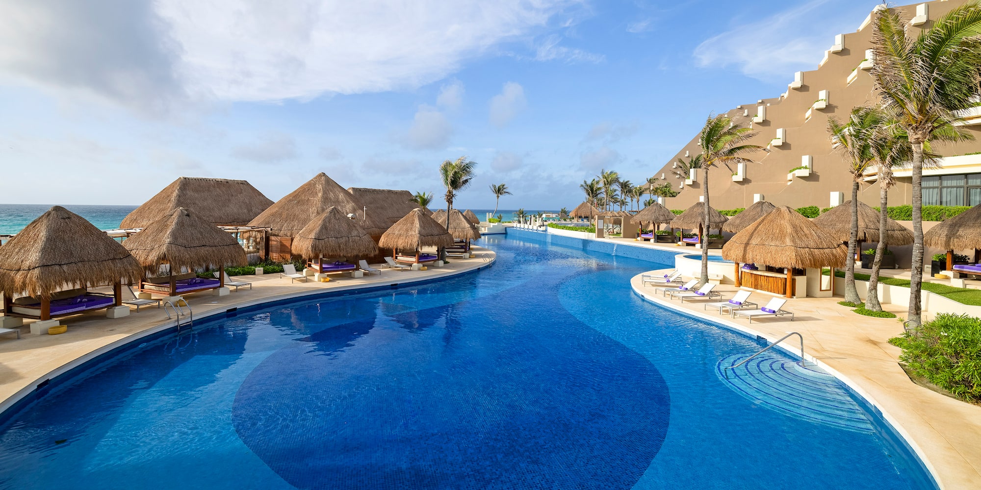 a pool with straw huts and a beach