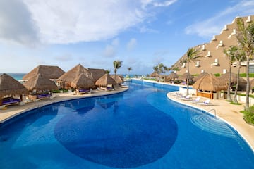 a pool with straw huts and a beach