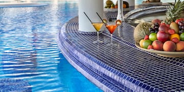 a pool with a bowl of fruit and a plate of fruit on the side