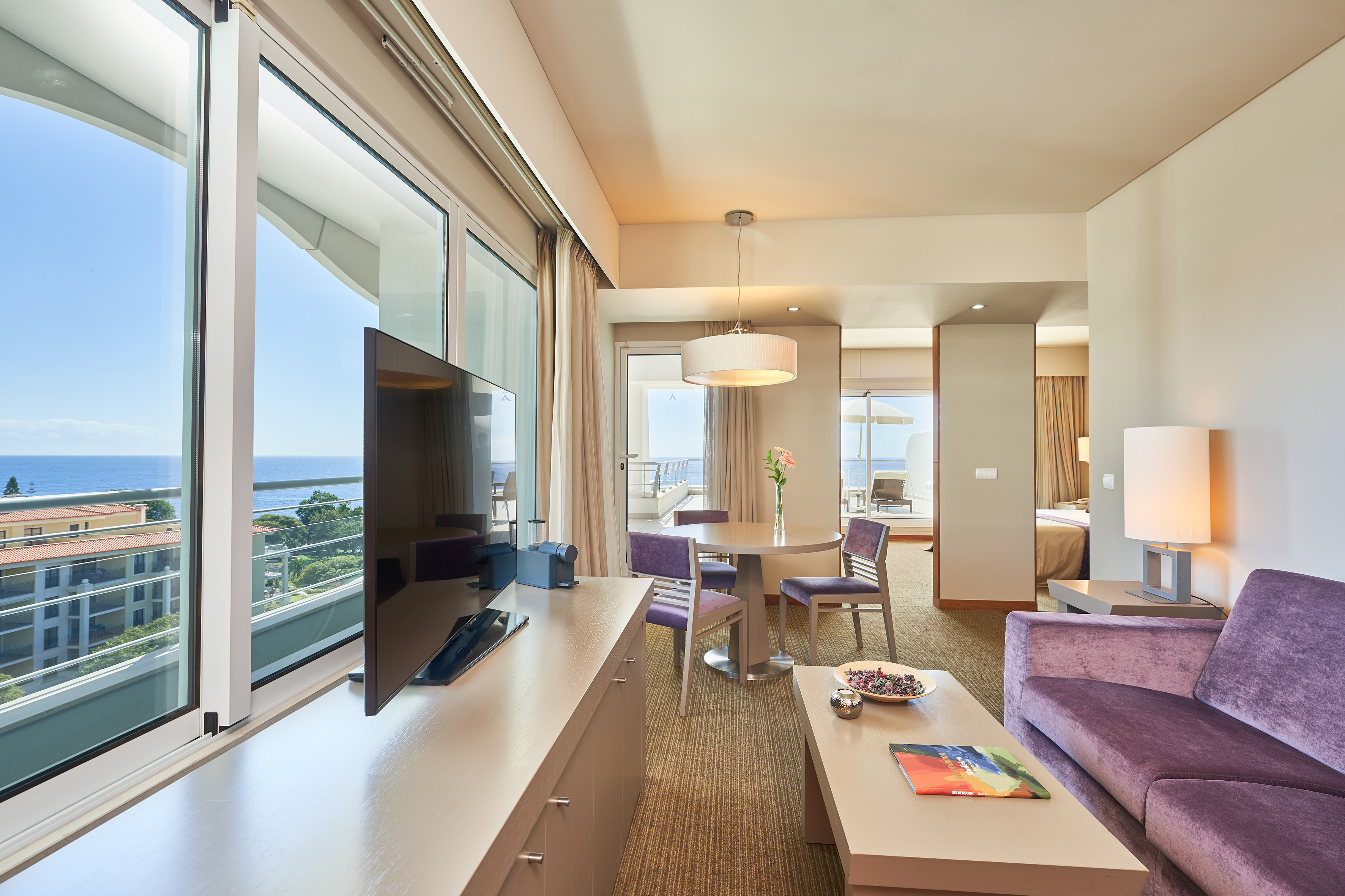 Hotel suite with ocean view, purple living room and dining area.