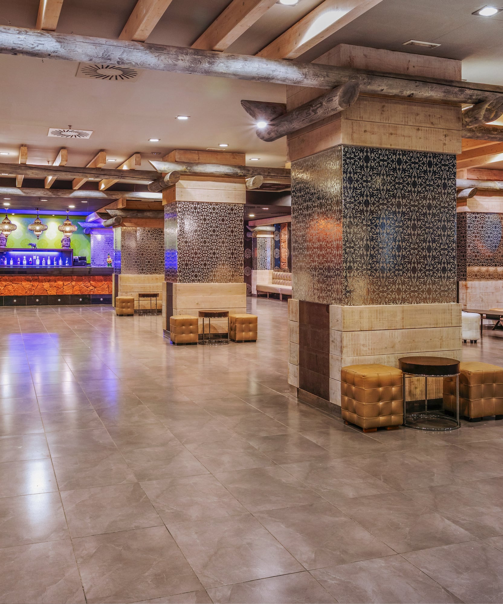 Hotel lobby bar with patterned columns, wooden beams, and lounge seating.