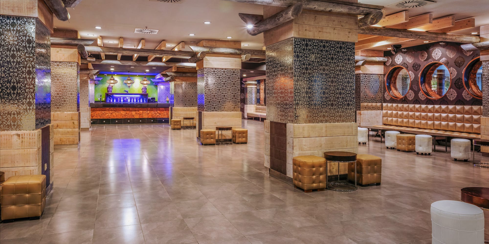 Spacious hotel lobby with rustic wood beams, patterned columns, and modern lounge seating.