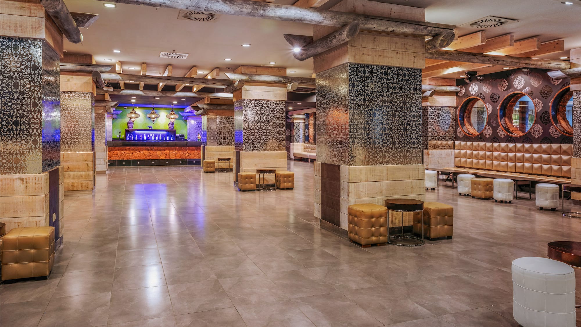 Spacious hotel lobby with rustic wood beams, patterned columns, and modern lounge seating.