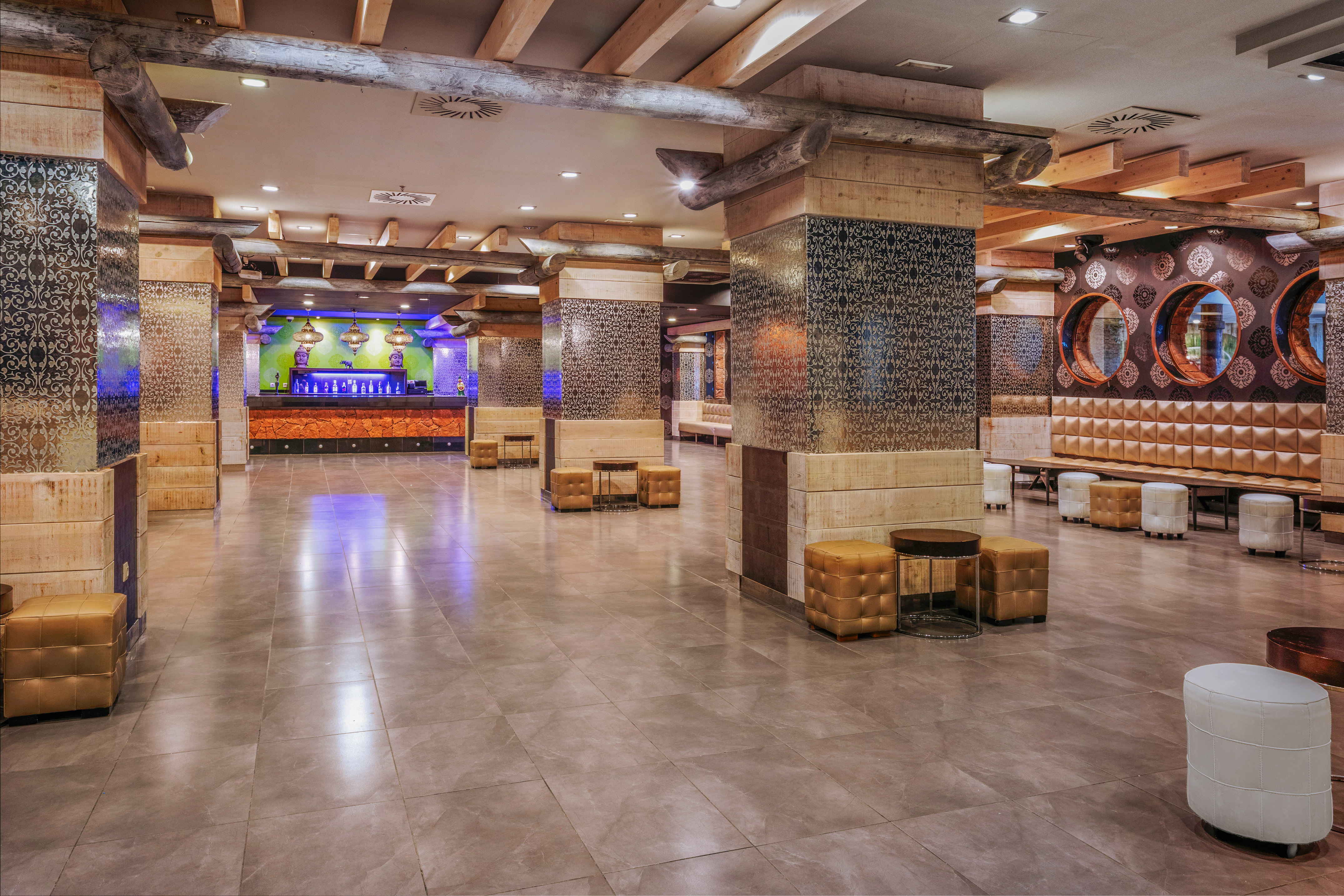 Hotel lobby bar with patterned columns, wooden beams, and lounge seating.