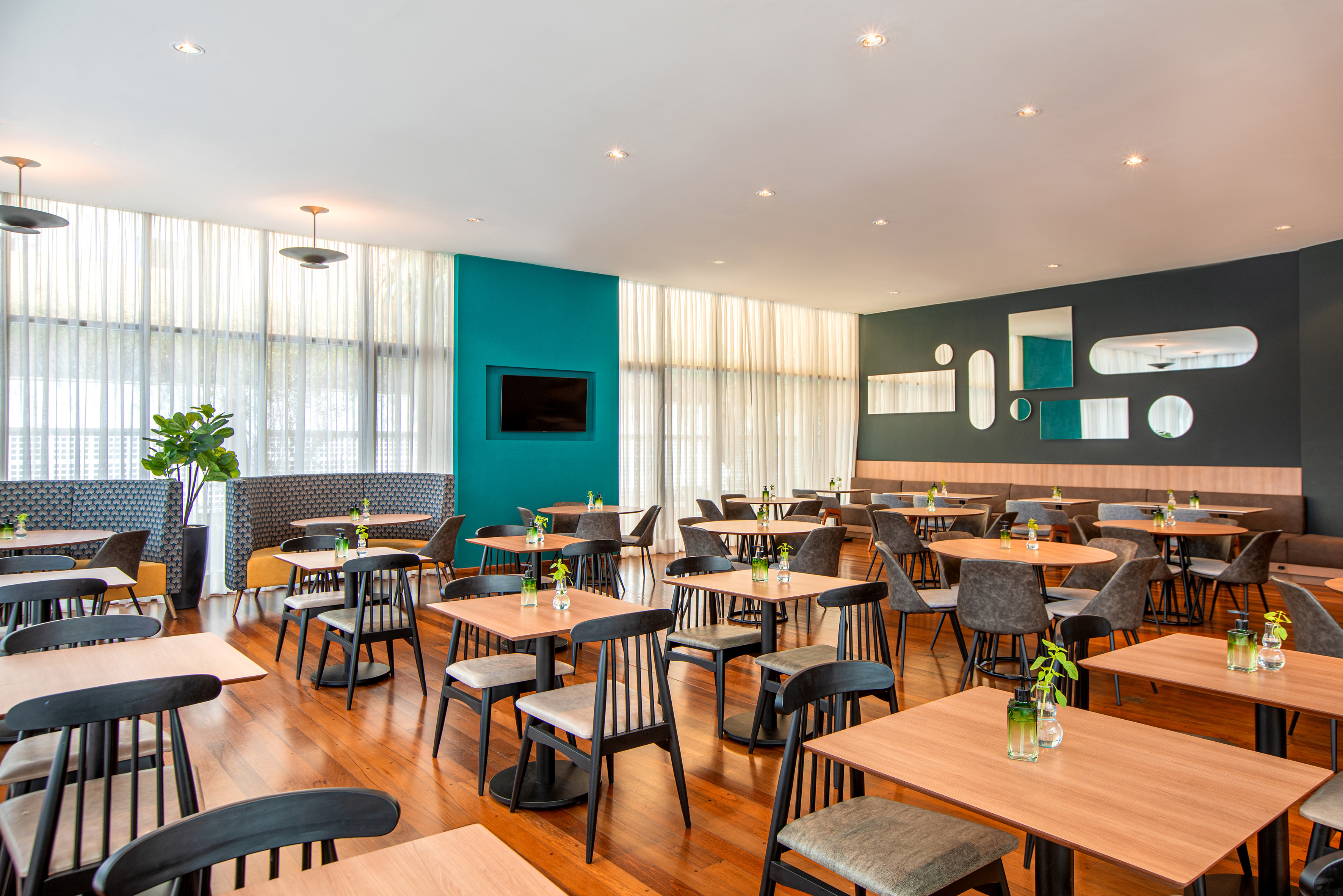 Modern restaurant dining room with wooden tables, chairs, and stylish decor.