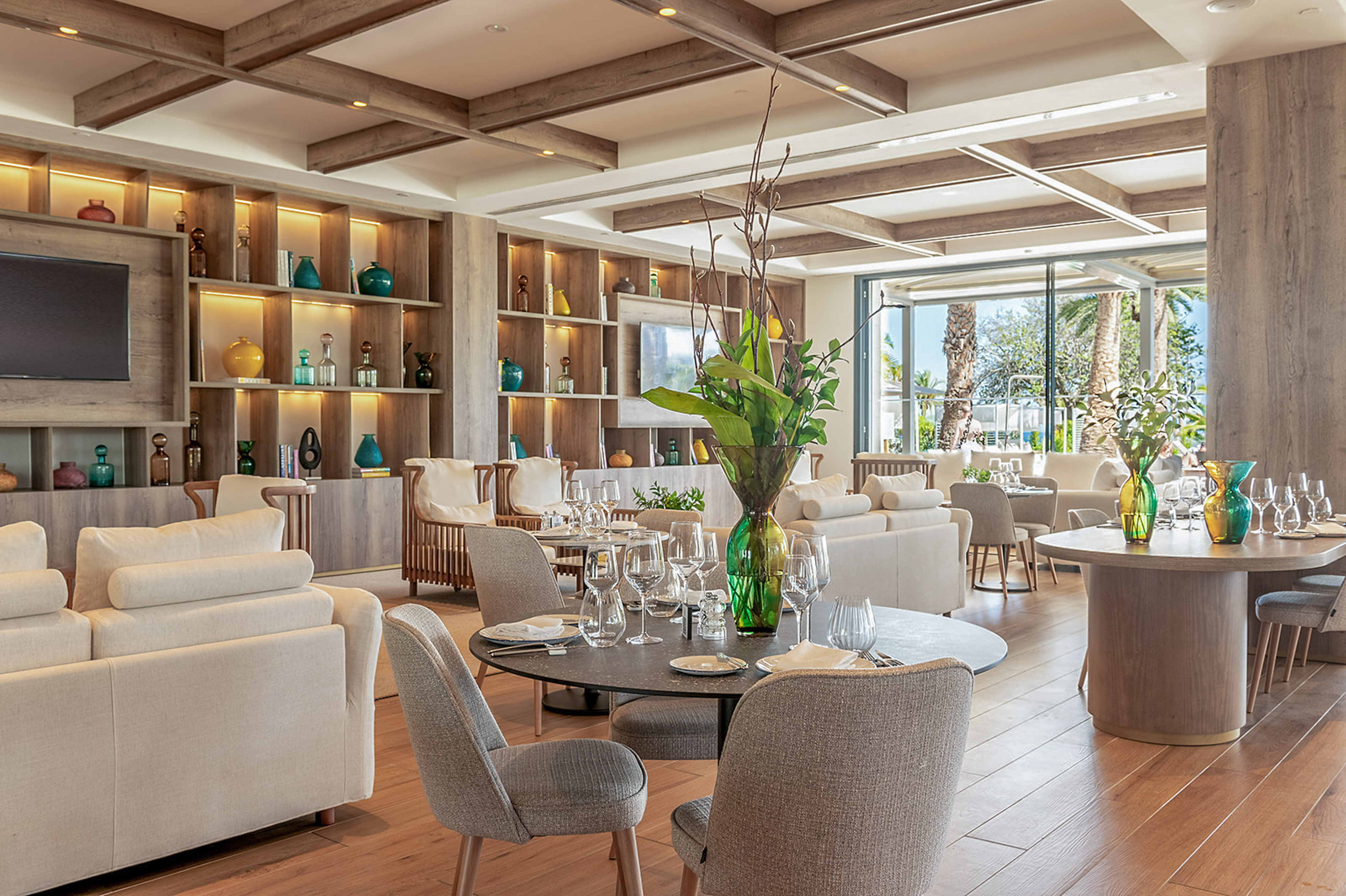 Bright modern restaurant lounge interior with wood, cream sofas, and dining tables.