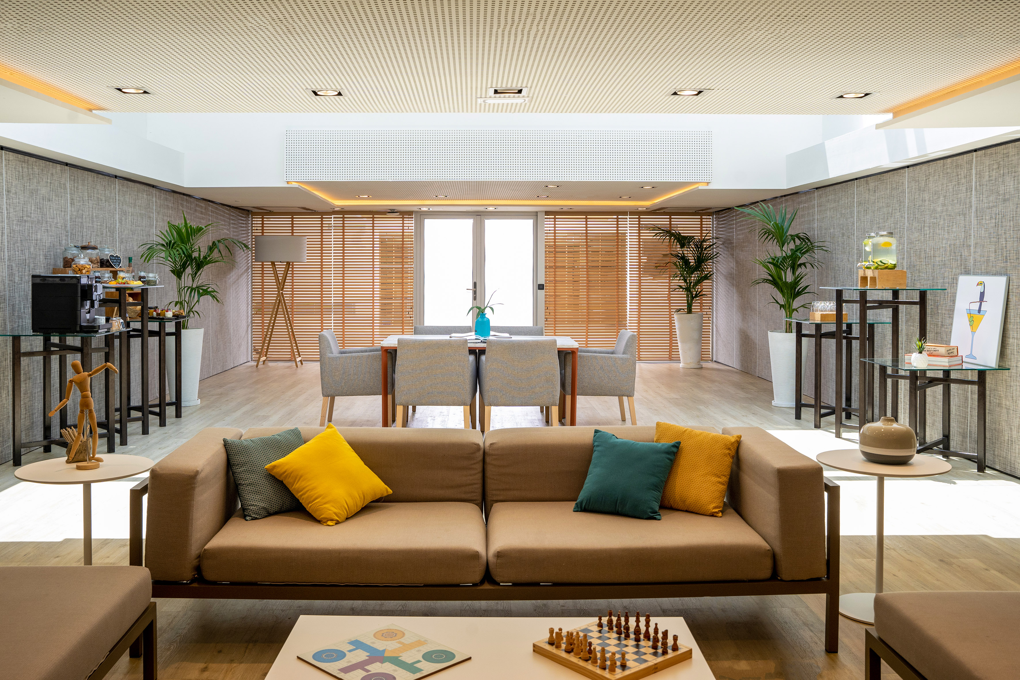 Modern lounge with sofa, board games, dining area, and coffee station.