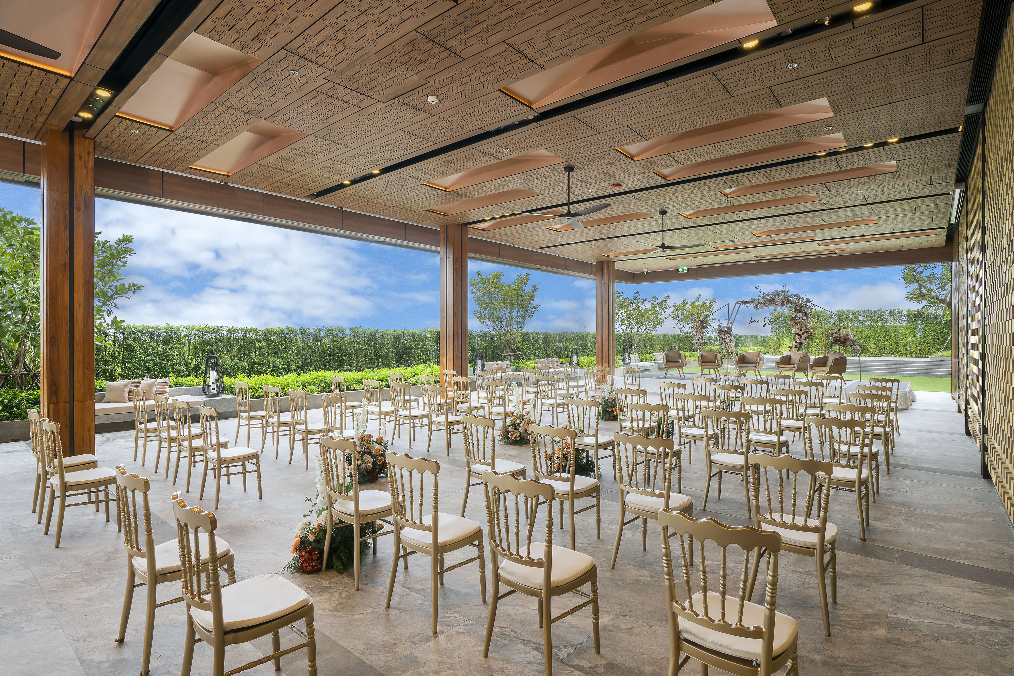 Elegant open-air wedding venue with rows of chairs, floral decor, and garden views.
