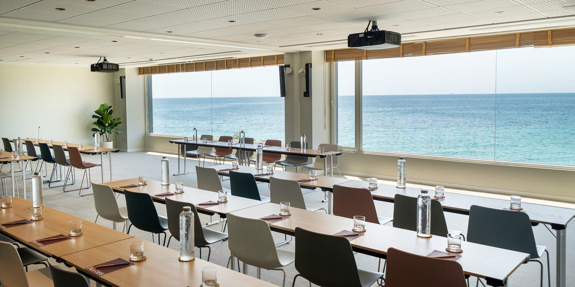 a room with tables and chairs and a large window overlooking the ocean