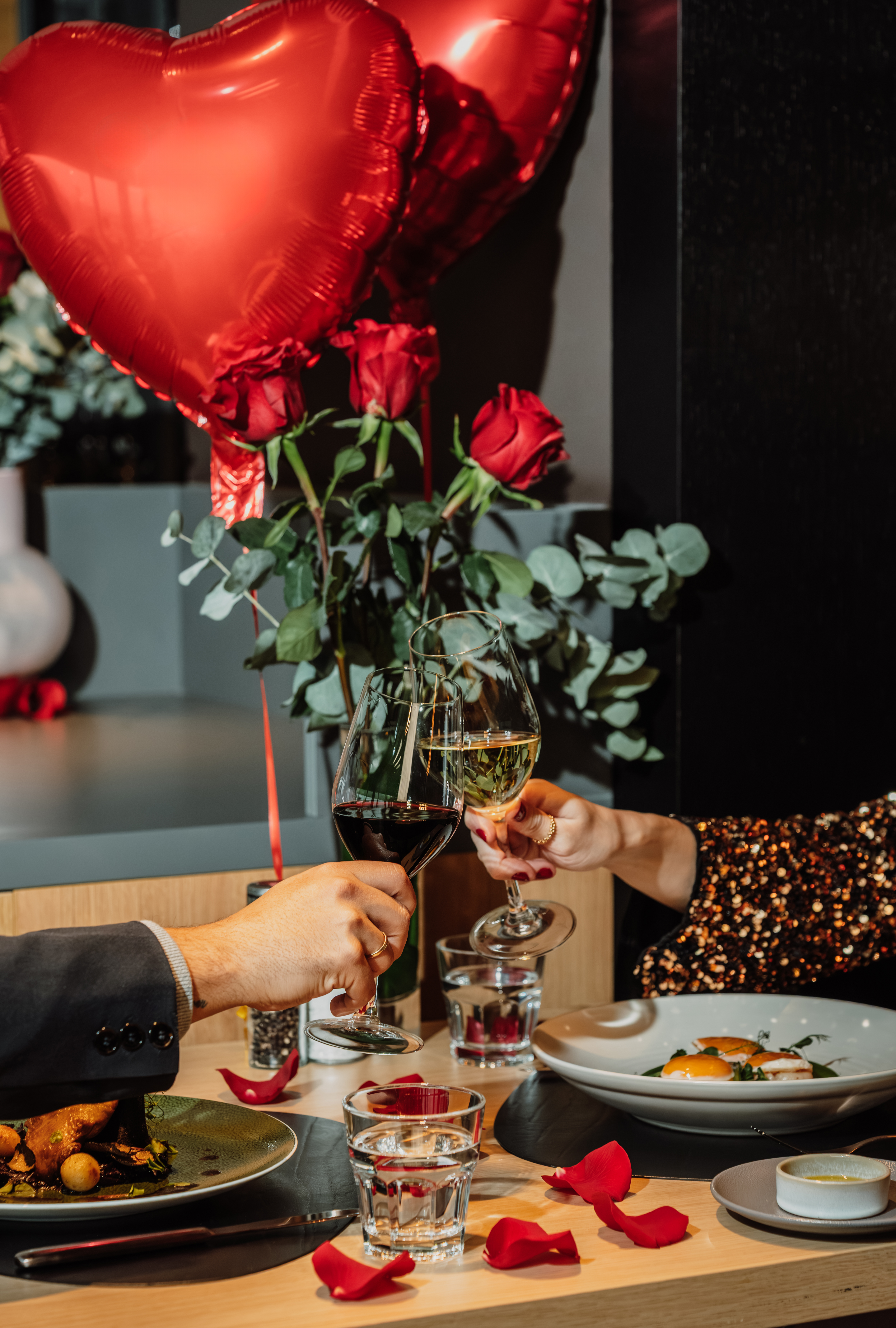 a couple holding wine glasses and a red balloon