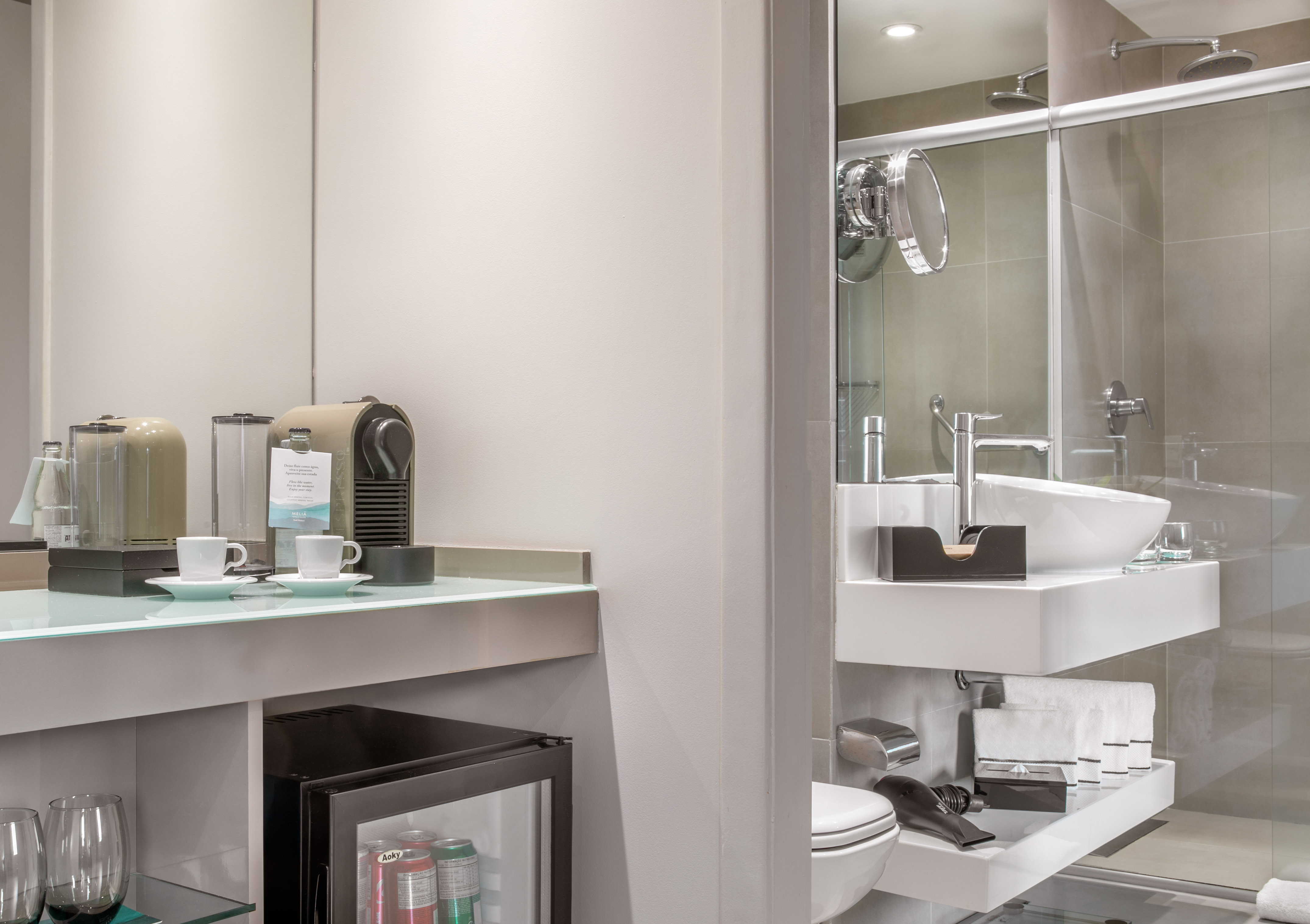 Modern hotel room: Nespresso coffee station, mini-fridge, and elegant bathroom with shower.