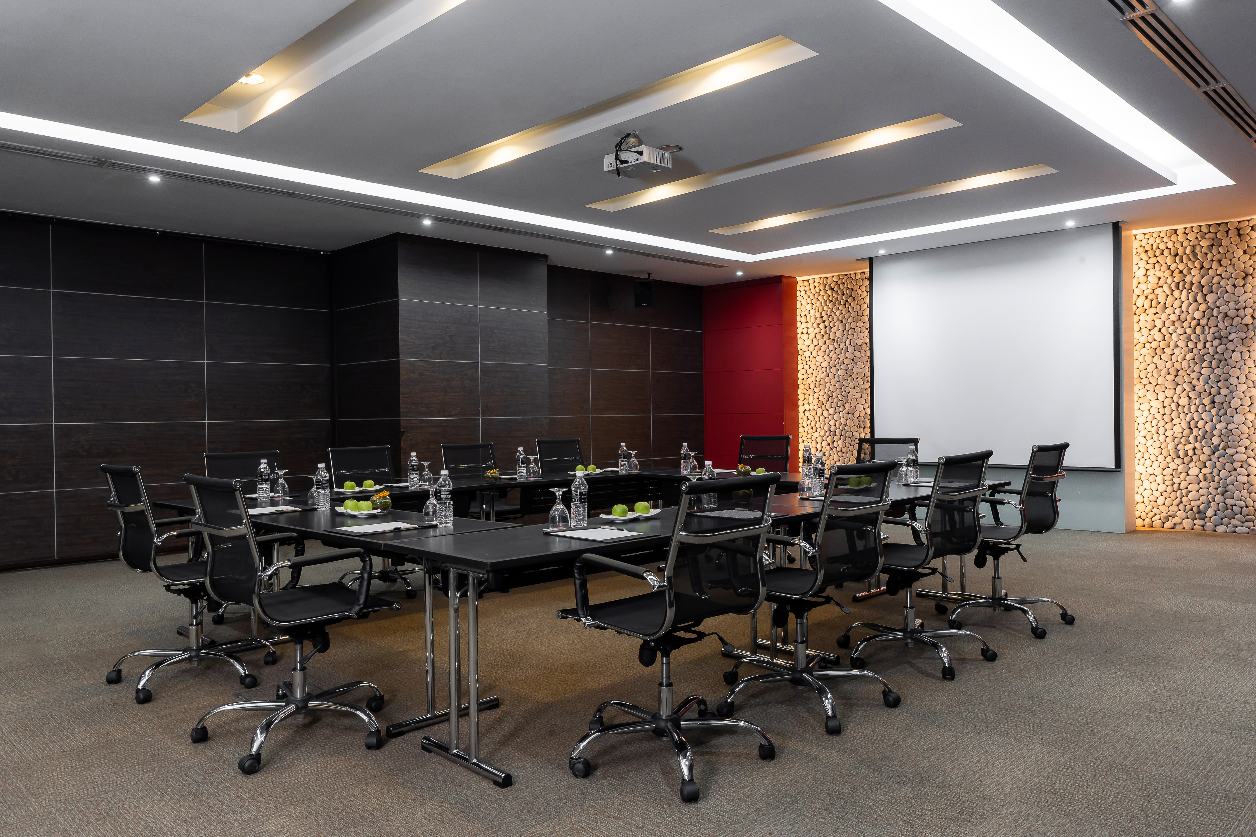 Modern executive meeting room with U-shaped table and projector screen.