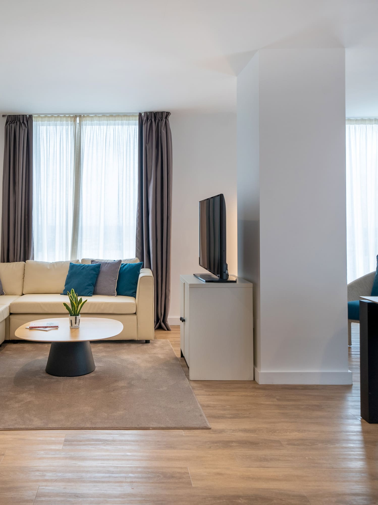 Modern living room with cream sofa, dining area, TV, and wall-mounted bicycle.