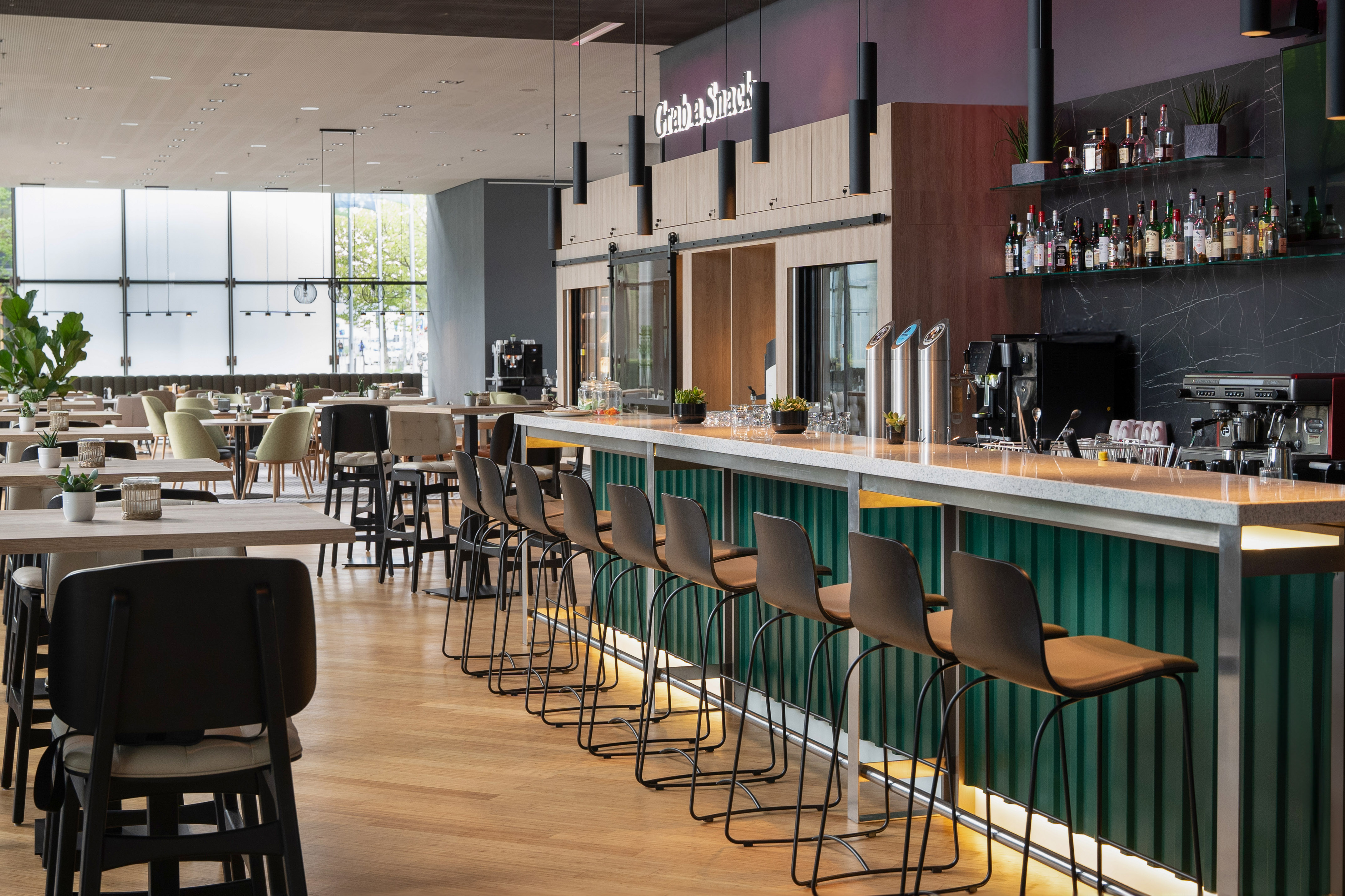 Modern bar and restaurant with green counter, stools, and dining tables.