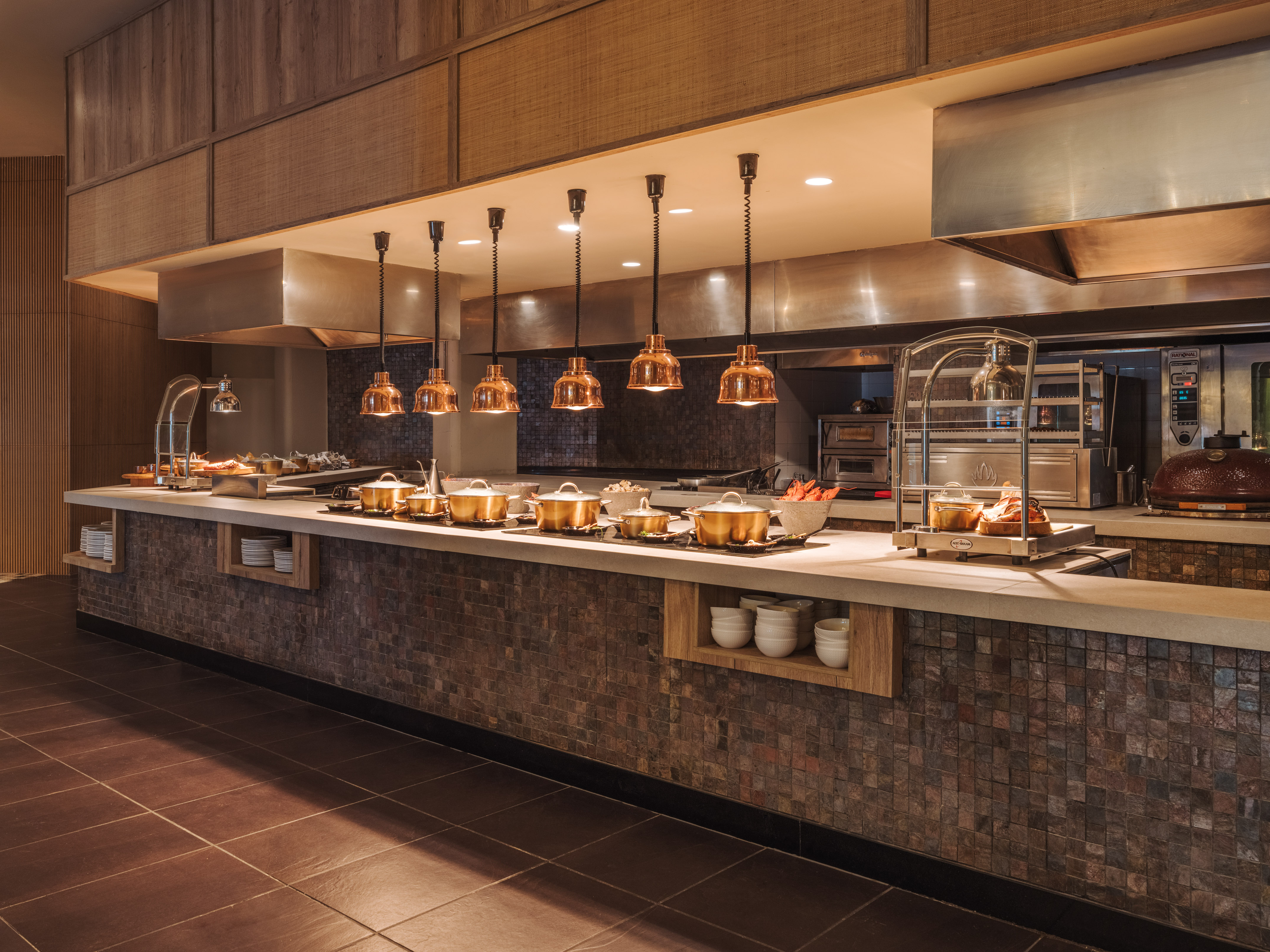 Hotel buffet serving line with copper food warmers and commercial kitchen.