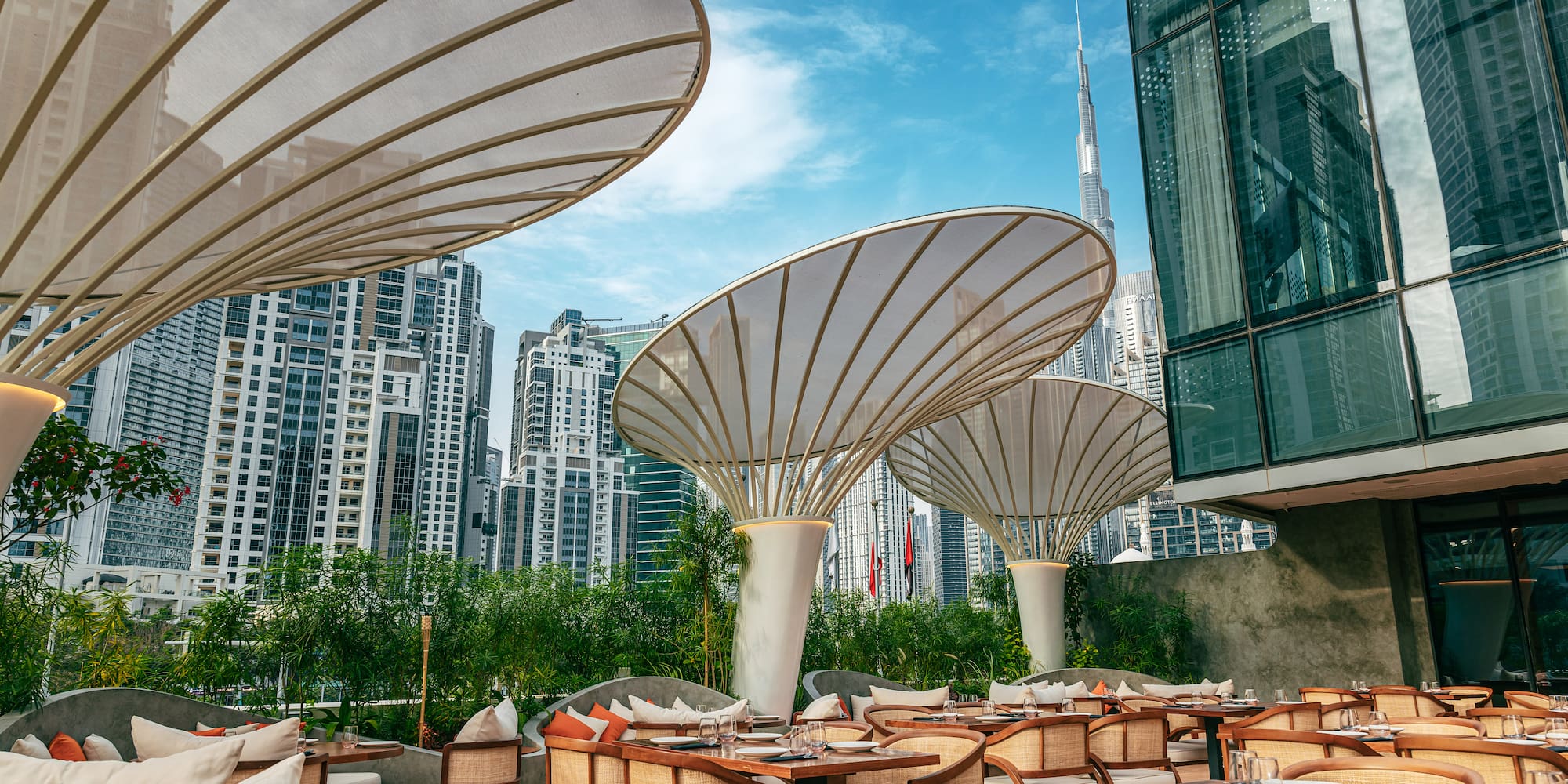 Dubai outdoor restaurant with elegant shade umbrellas, Burj Khalifa view.