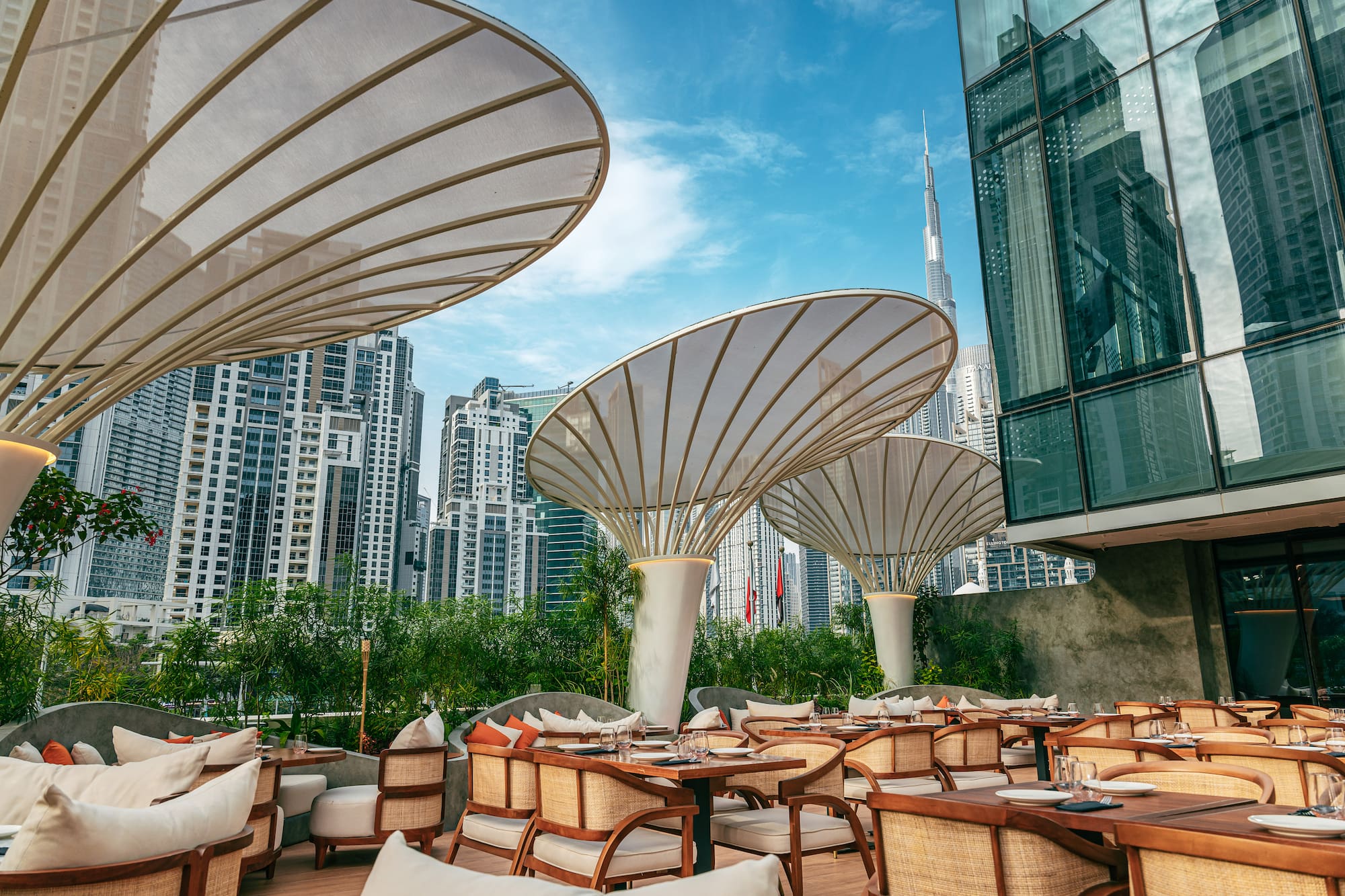 Dubai outdoor restaurant with elegant shade umbrellas, Burj Khalifa view.