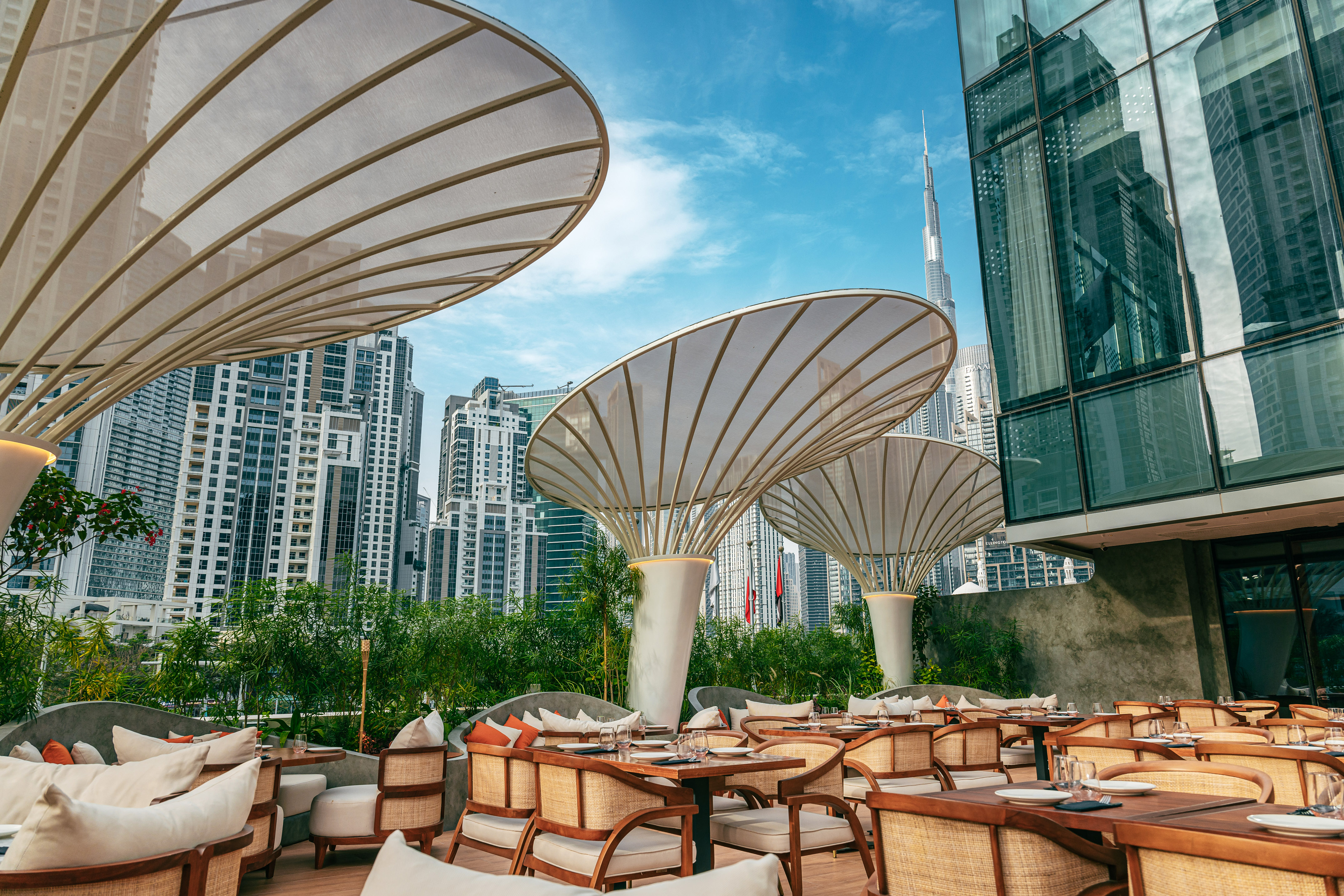 Dubai outdoor restaurant with elegant shade umbrellas, Burj Khalifa view.
