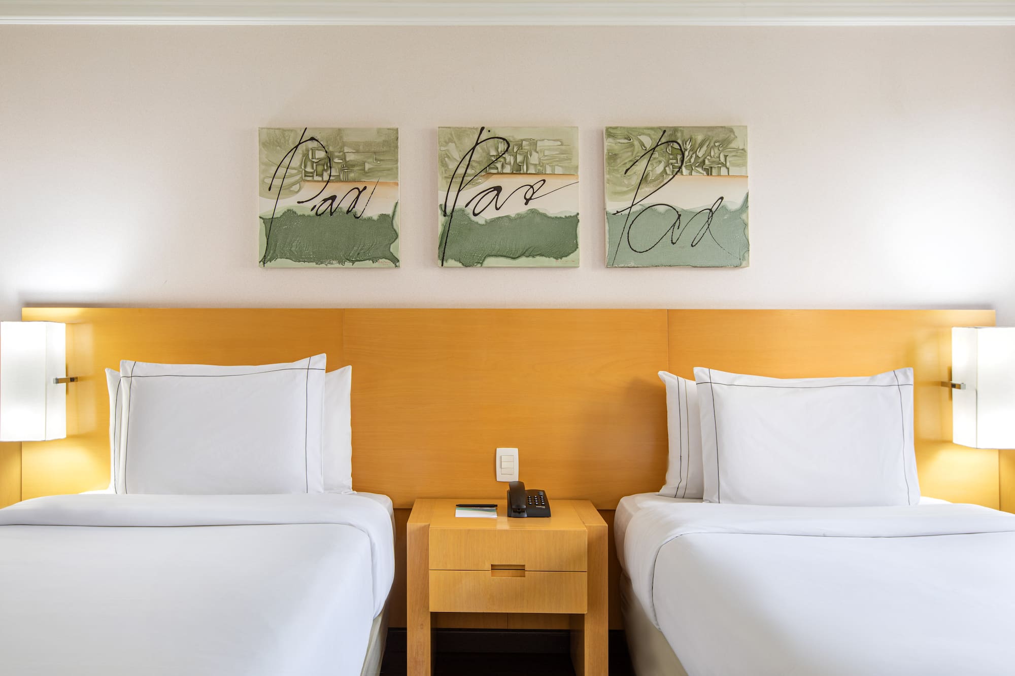 two beds with white sheets and a nightstand