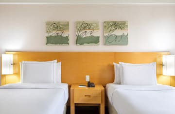 two beds with white sheets and a nightstand