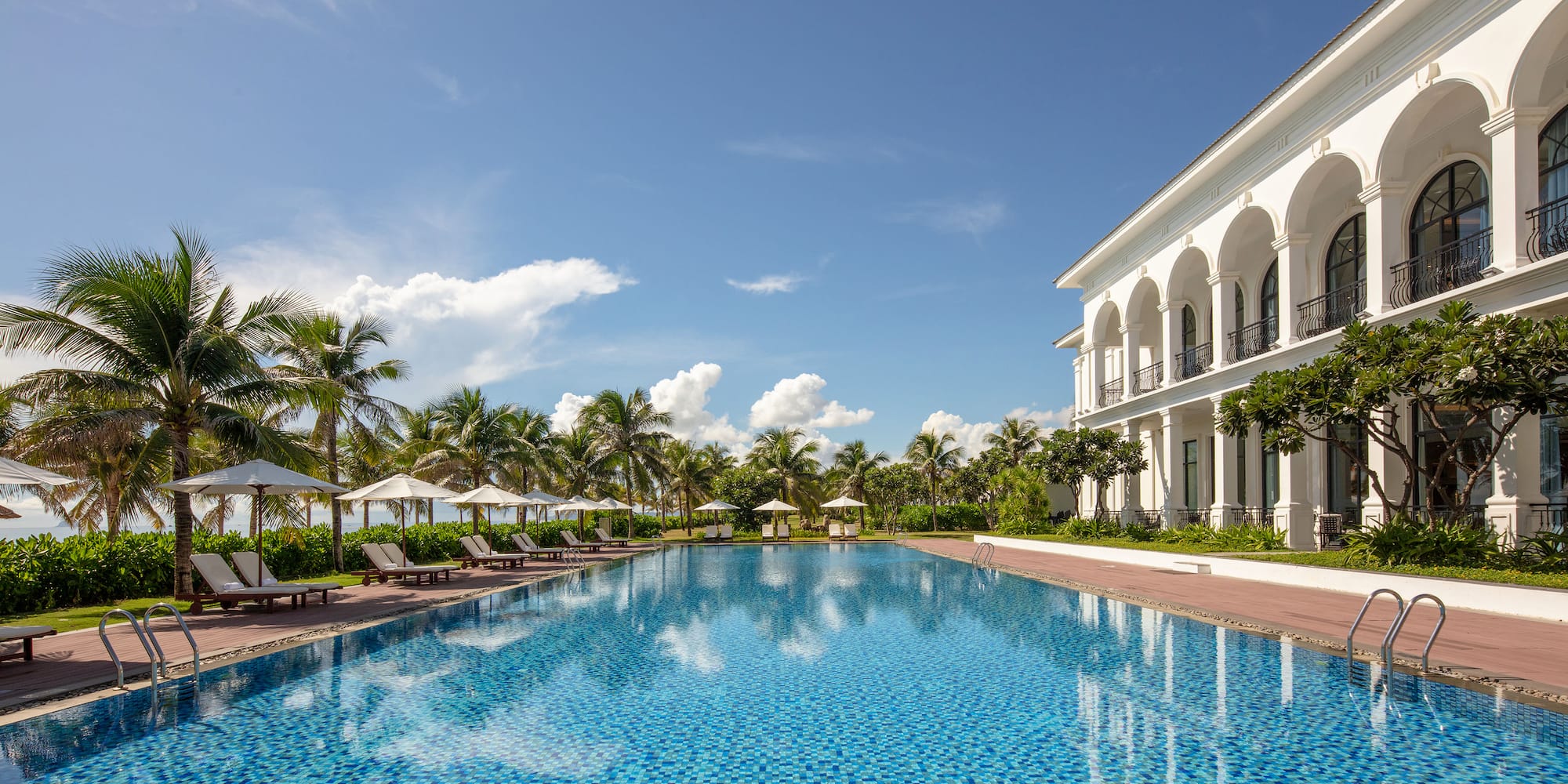 a pool with chairs and a building in the background