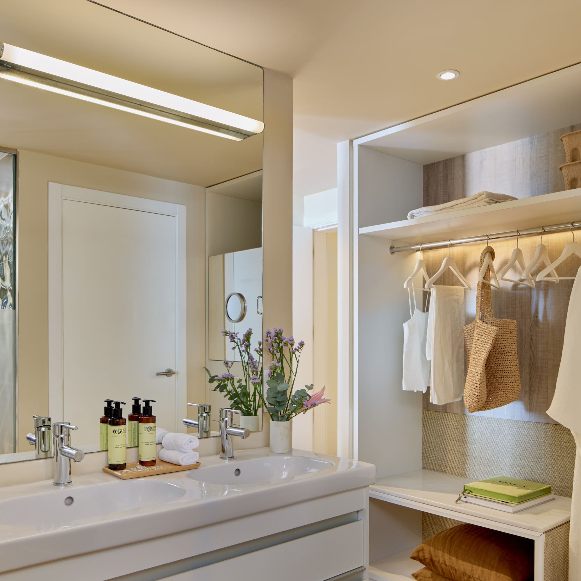 Modern hotel bathroom with double sink vanity and integrated open closet.