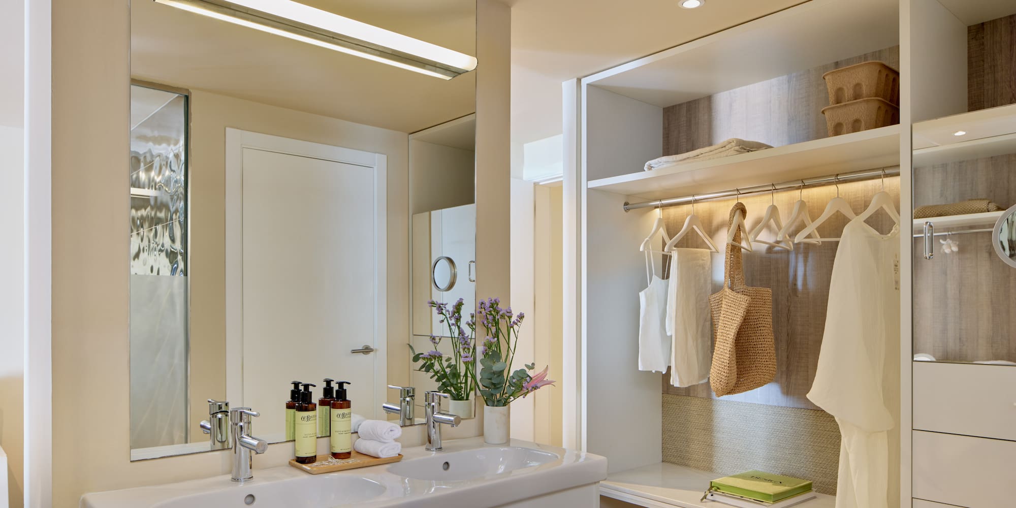 Modern hotel bathroom with double sink vanity and integrated open closet.