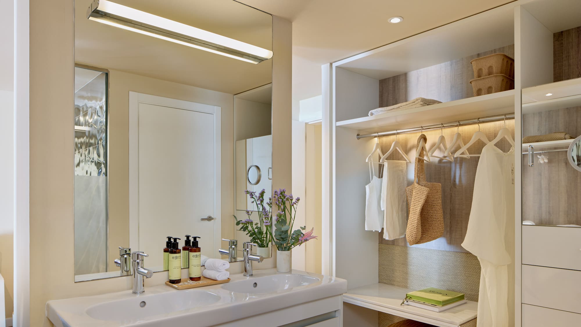 Modern hotel bathroom with double sink vanity and integrated open closet.