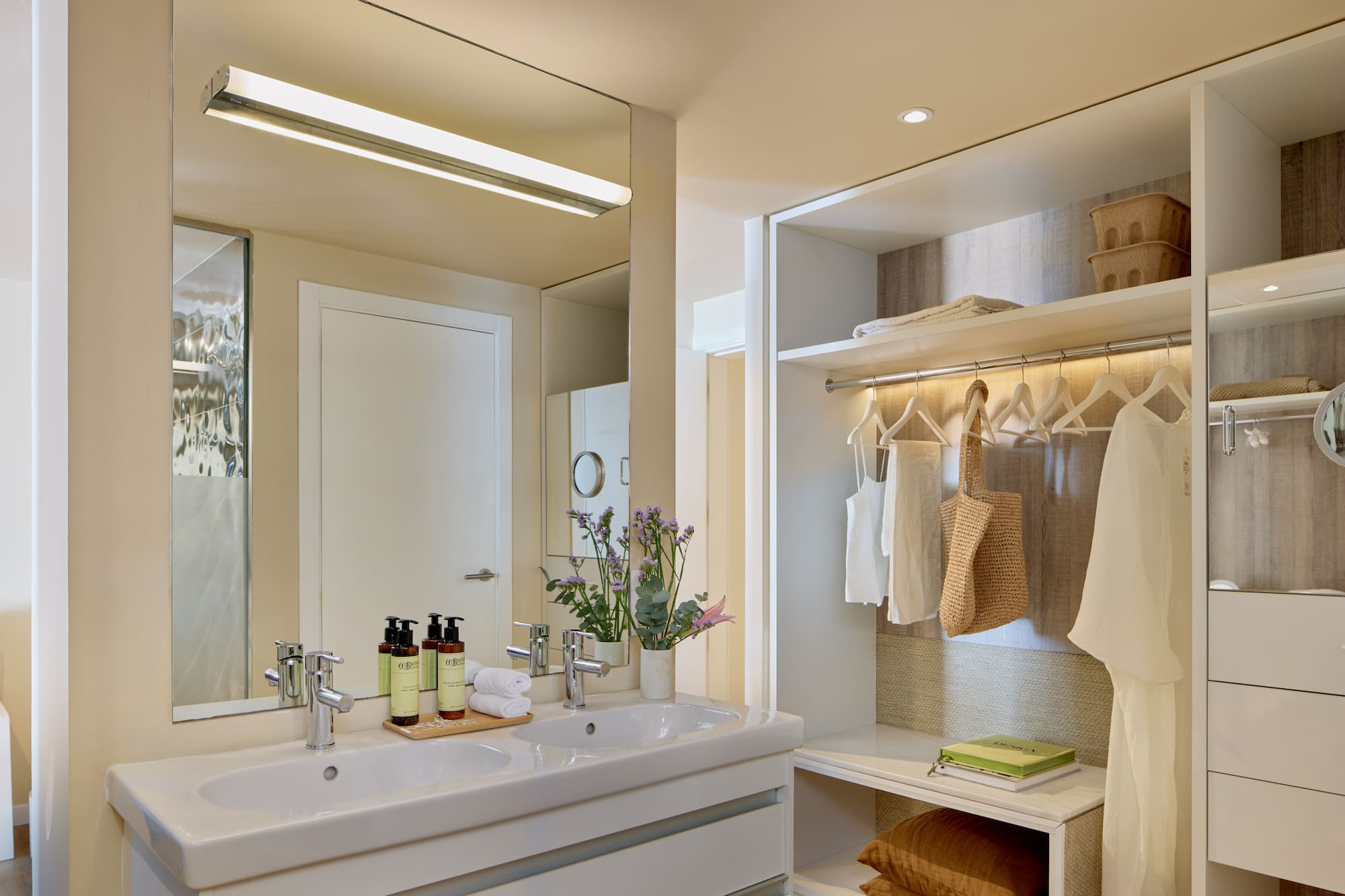 Modern hotel bathroom with double sink vanity and integrated open closet.