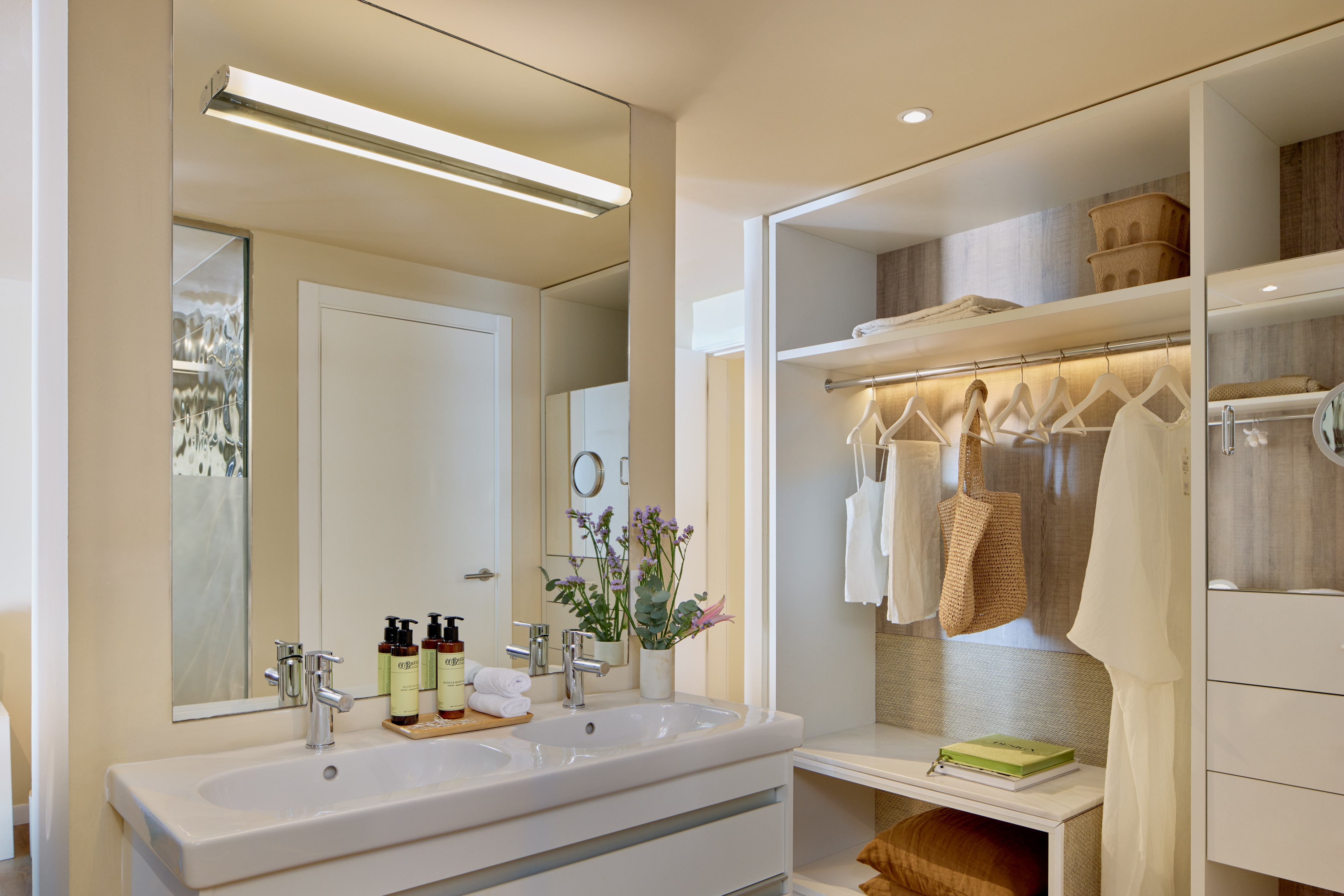 Modern hotel bathroom with double sink vanity and integrated open closet.