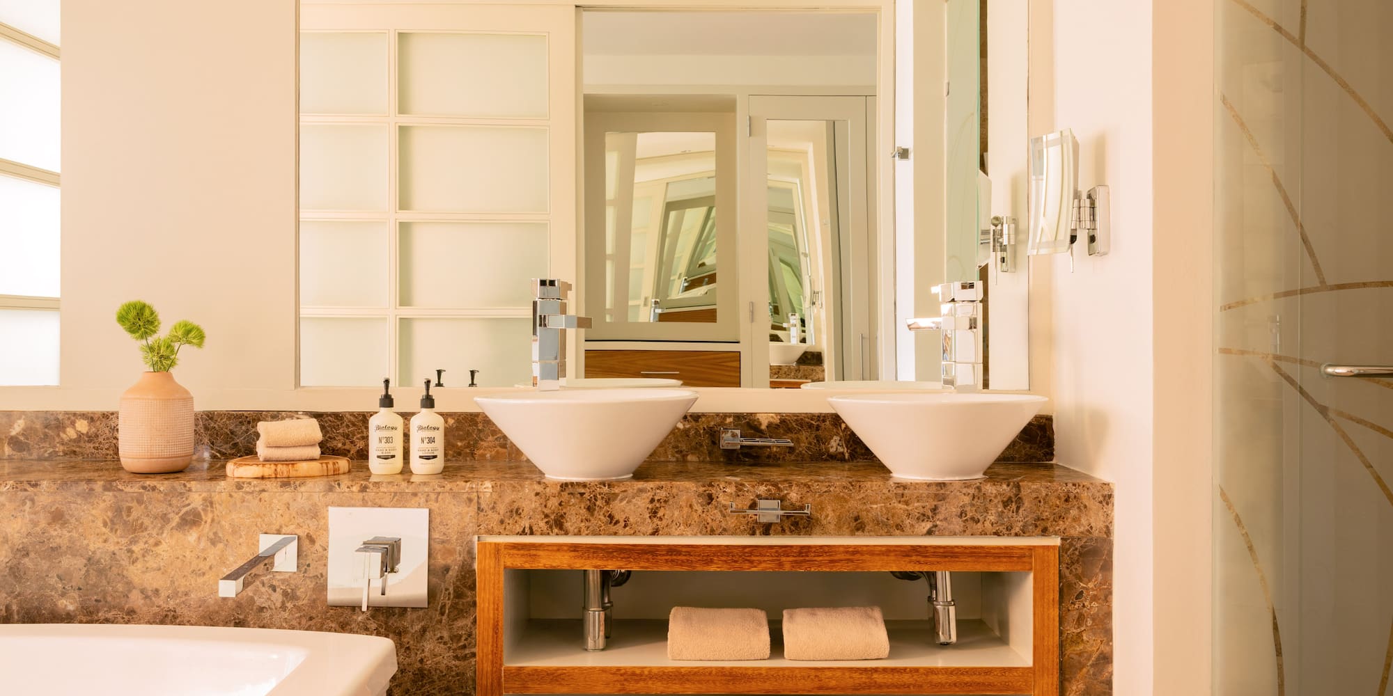 Luxurious modern bathroom with double vessel sinks, marble vanity, and bathtub.