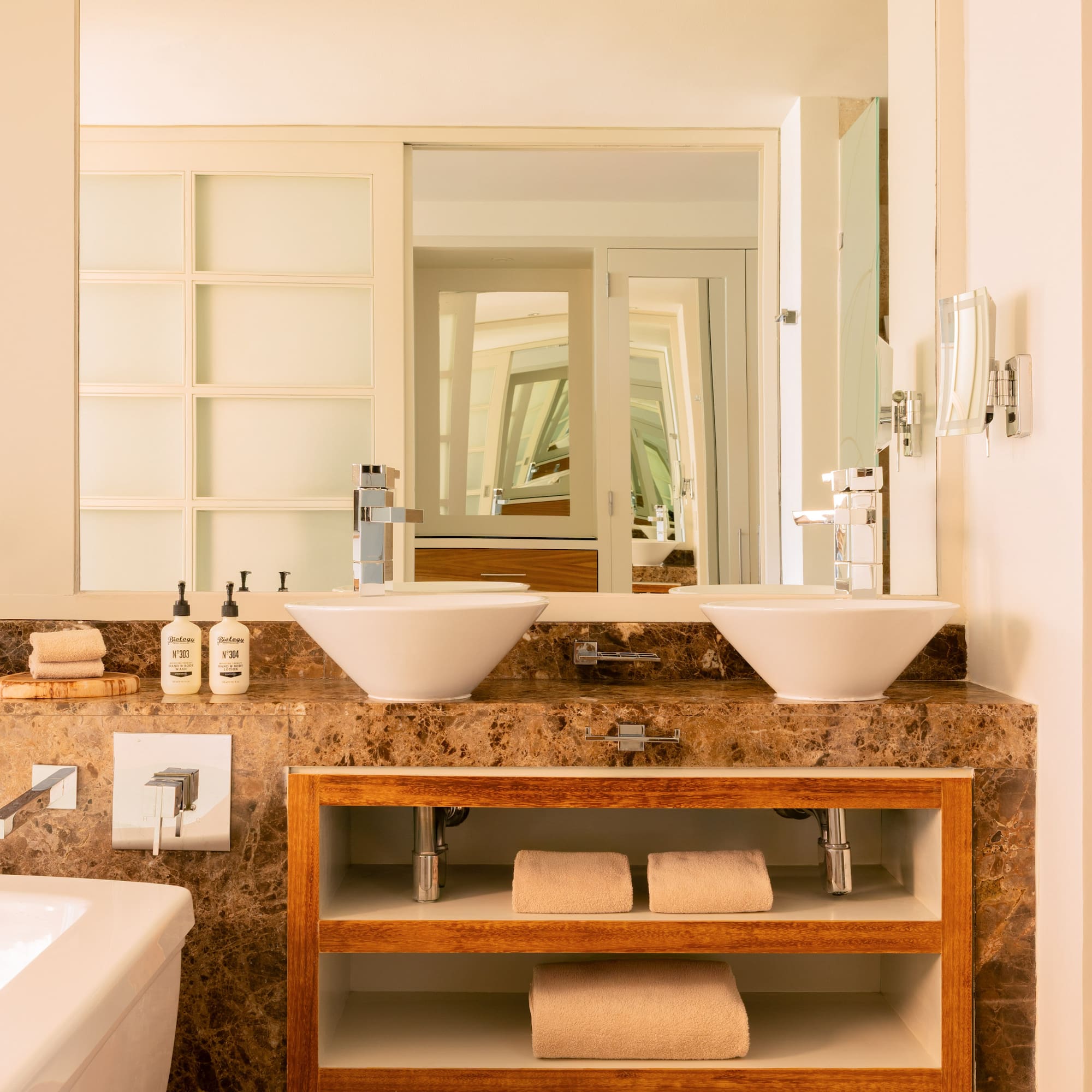 Elegant bathroom with twin vessel sinks, marble vanity, and wood shelving.