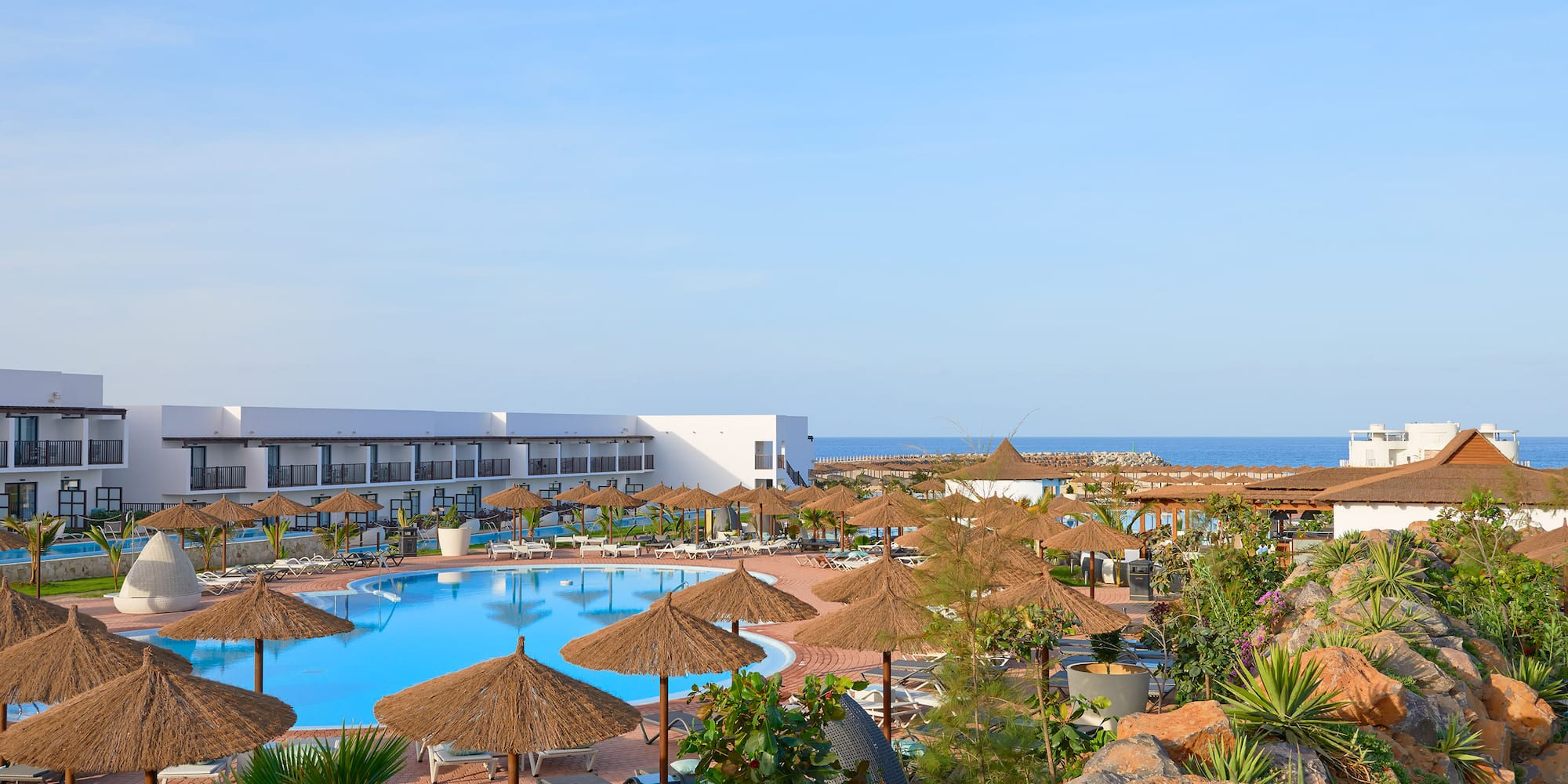 a pool with umbrellas and chairs and a building with a body of water
