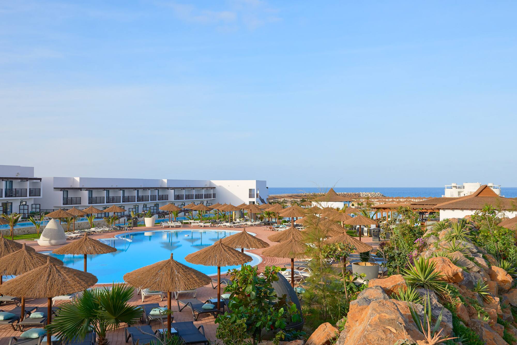 a pool with umbrellas and chairs and a building with a body of water