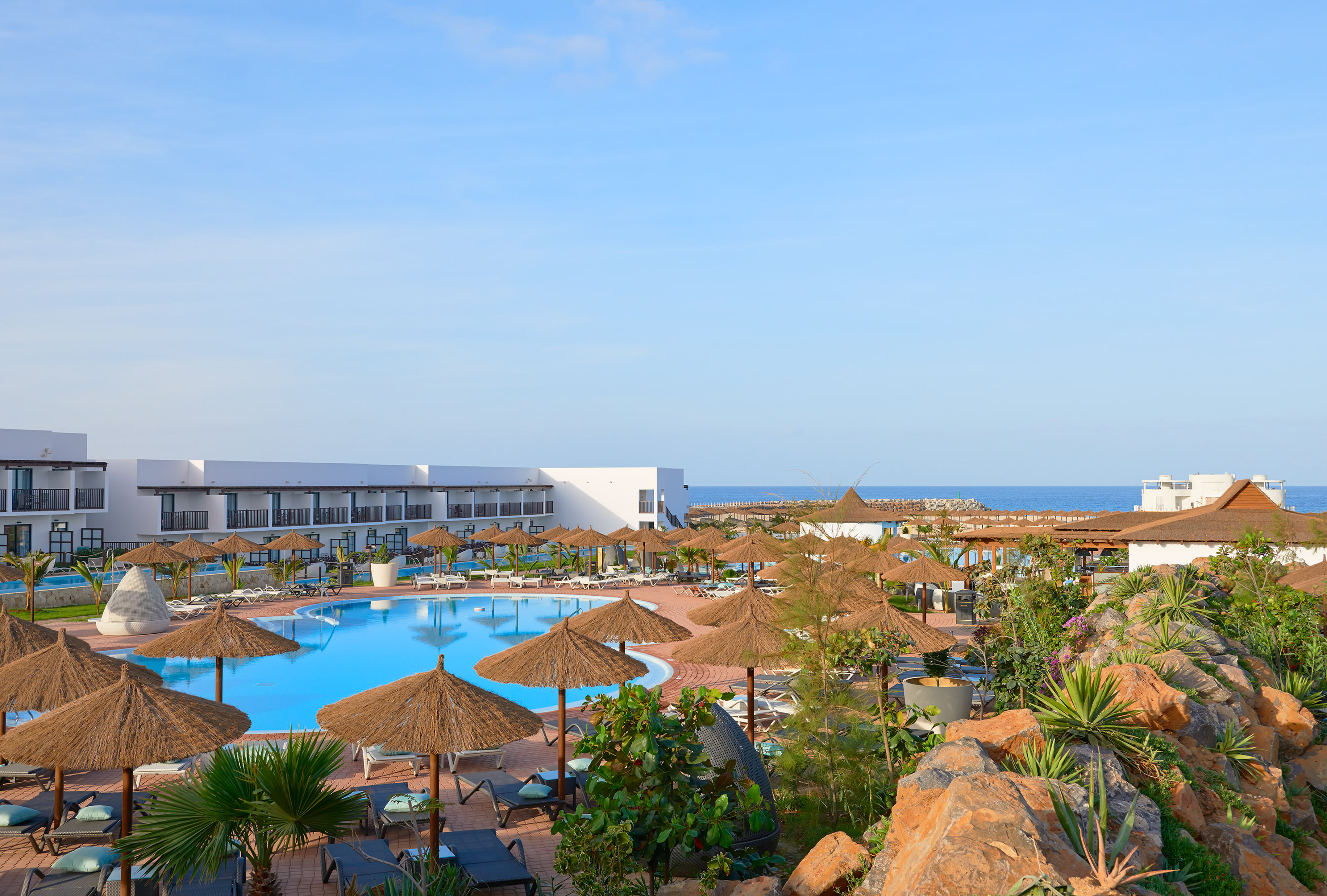 a pool with umbrellas and chairs and a building with a body of water