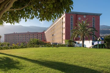 a large building with a lawn and trees