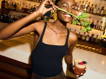a woman holding a stem in her mouth and holding a drink