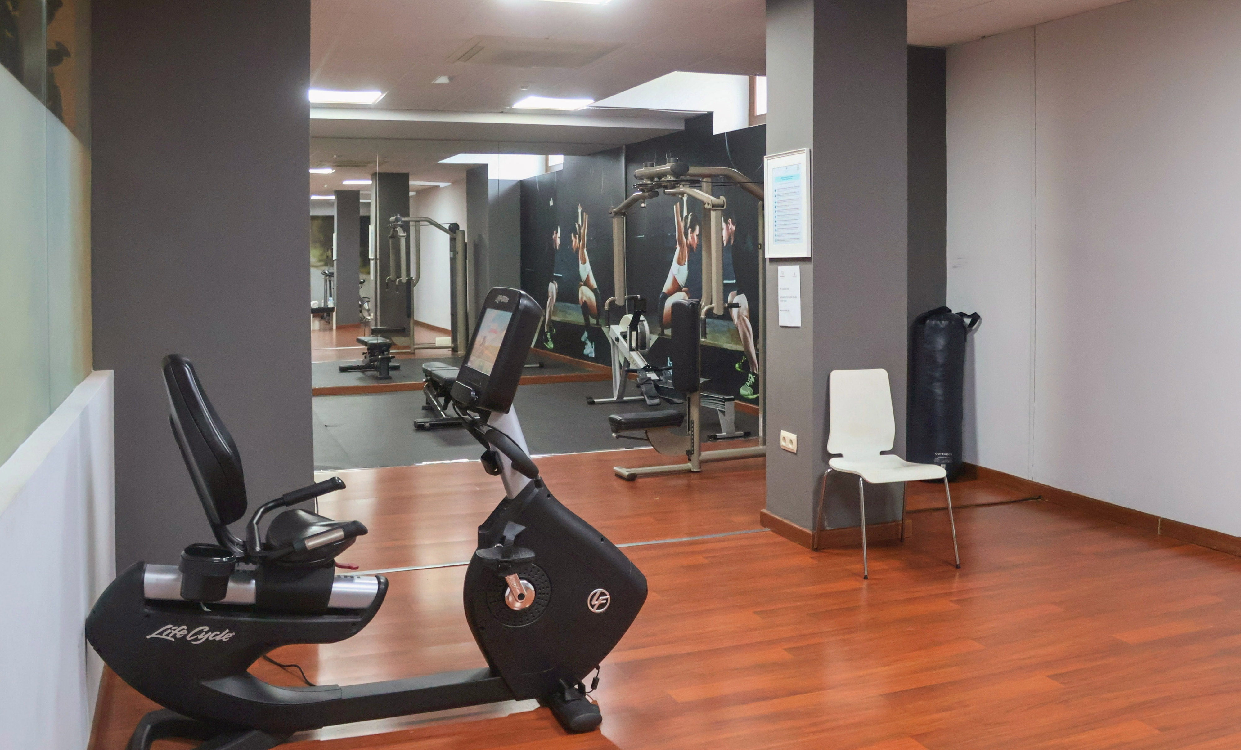 Modern gym interior with recumbent bike, weight machines, and mirrored walls.