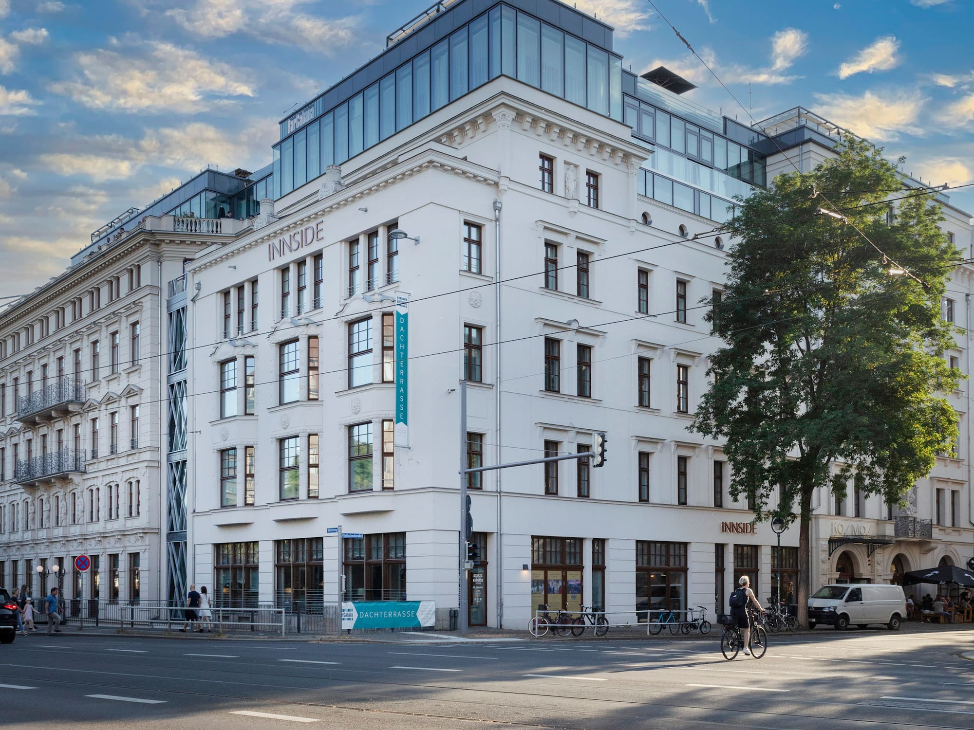 INNSIDE hotel, white building with modern glass rooftop, at a sunny urban intersection.