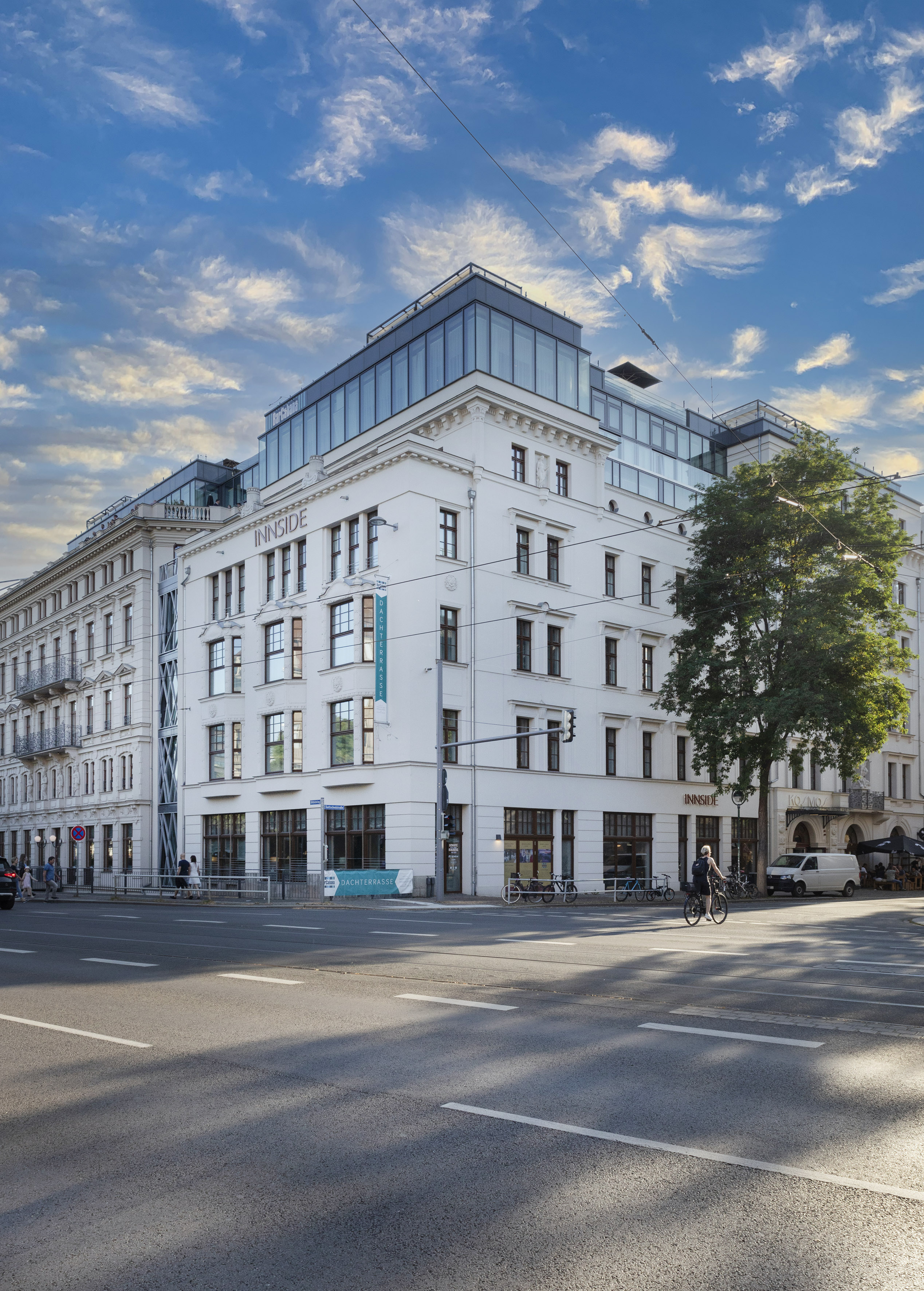 INNSIDE hotel, white building with modern glass rooftop, at a sunny urban intersection.