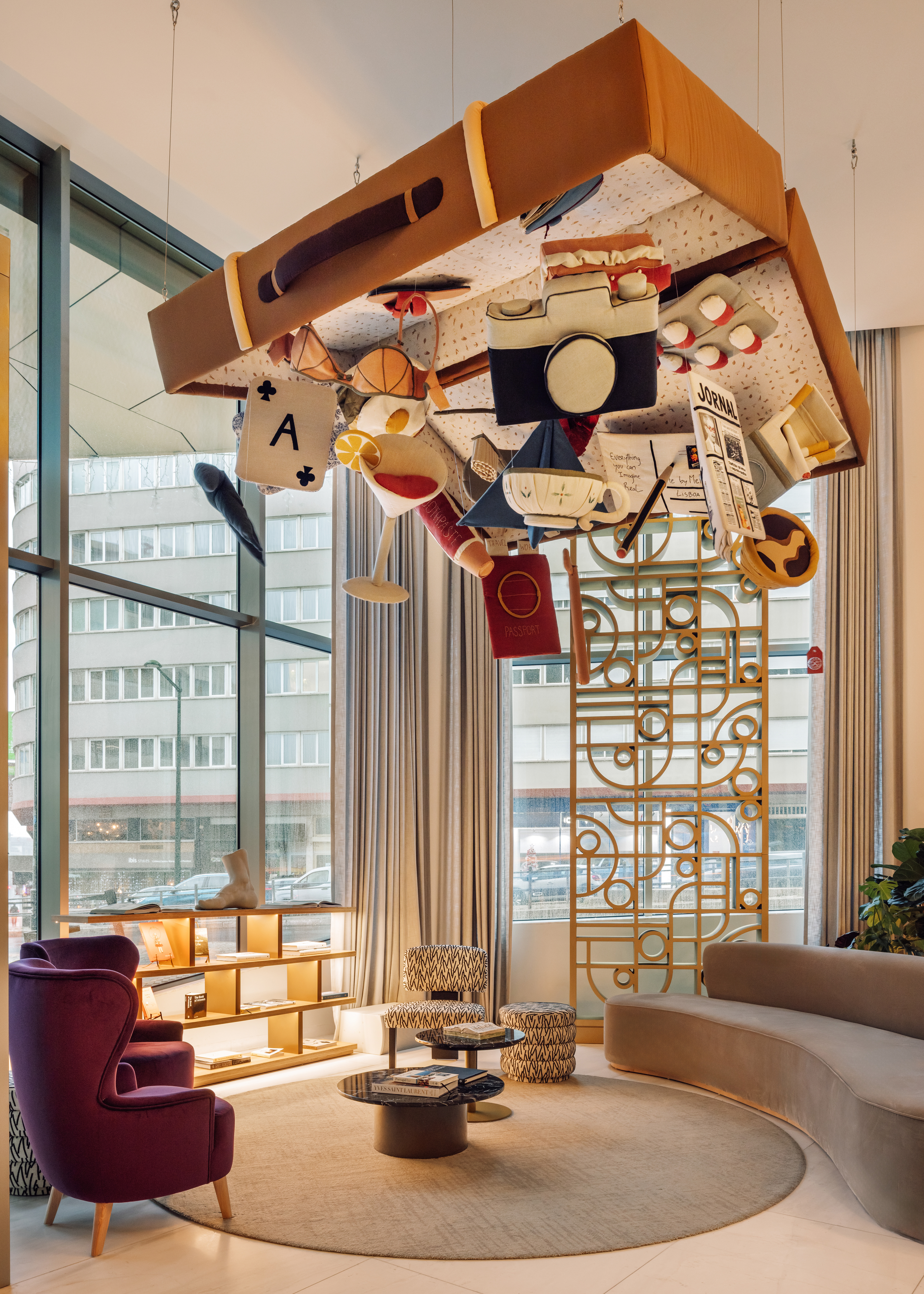 Whimsical hanging suitcase art in a modern hotel lobby lounge.