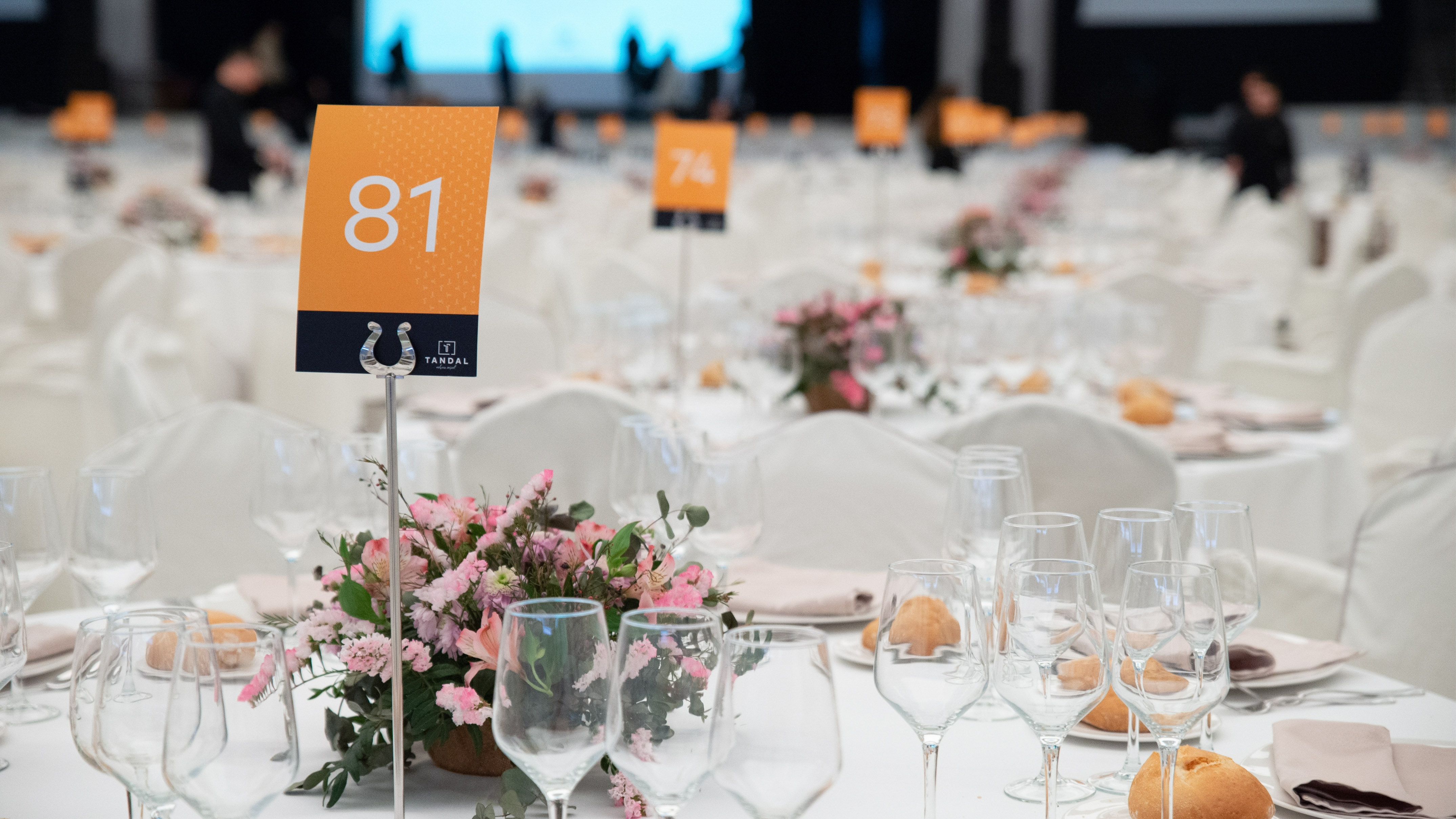 Formal event table setting with number 81, pink flowers, and glassware.