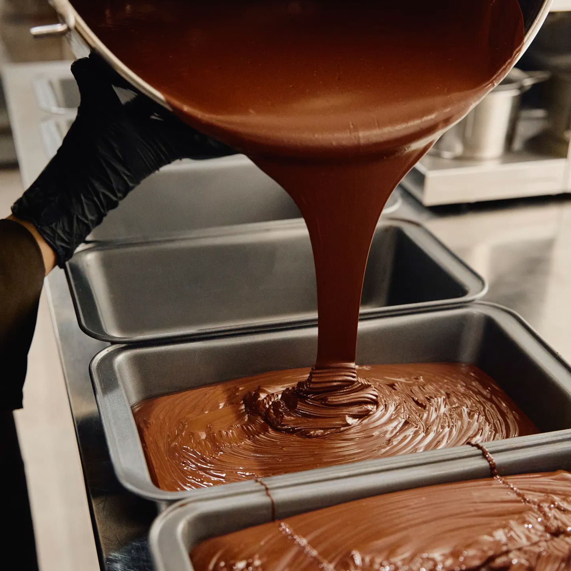 a person pouring chocolate into pans