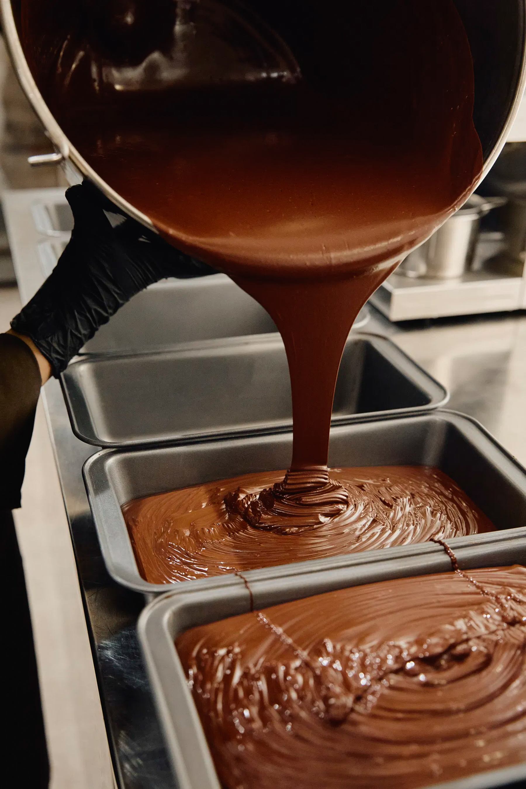 a person pouring chocolate into pans