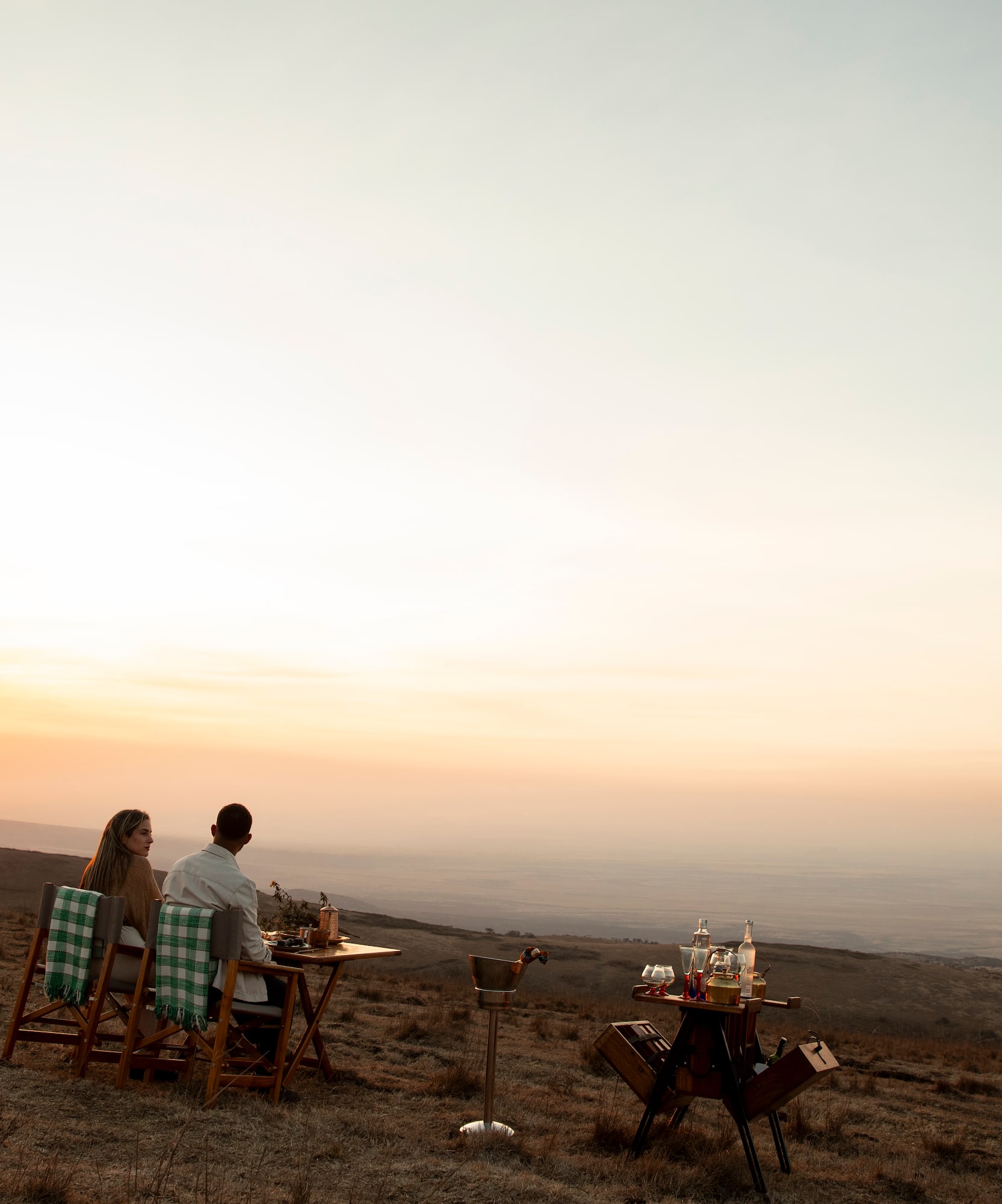 Cena romántica de pareja en la montaña al atardecer, paisaje africano.