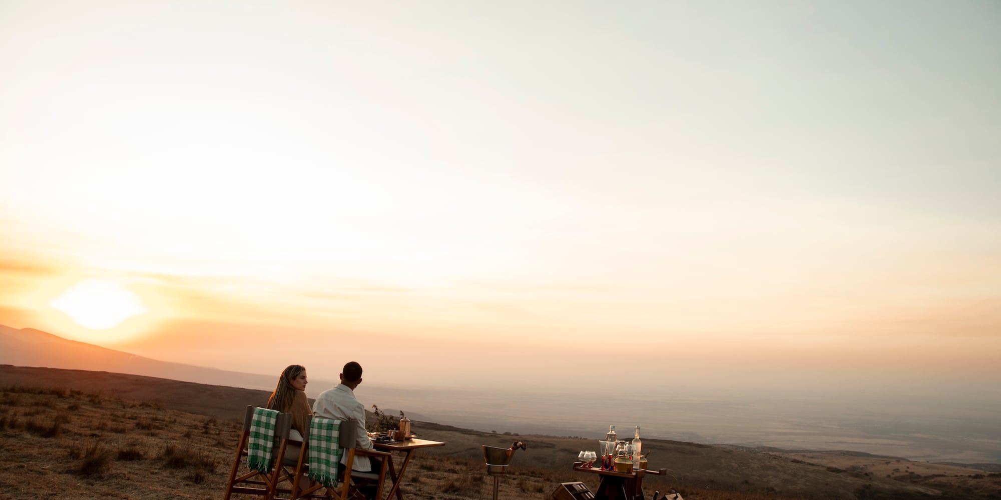 a man and woman sitting at a table in a field