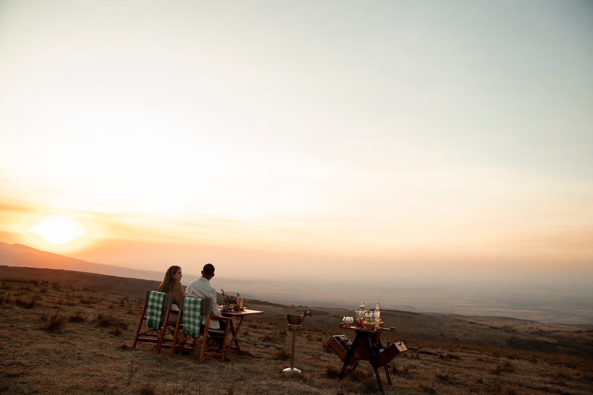 Cena romántica de pareja en la montaña al atardecer, paisaje africano.